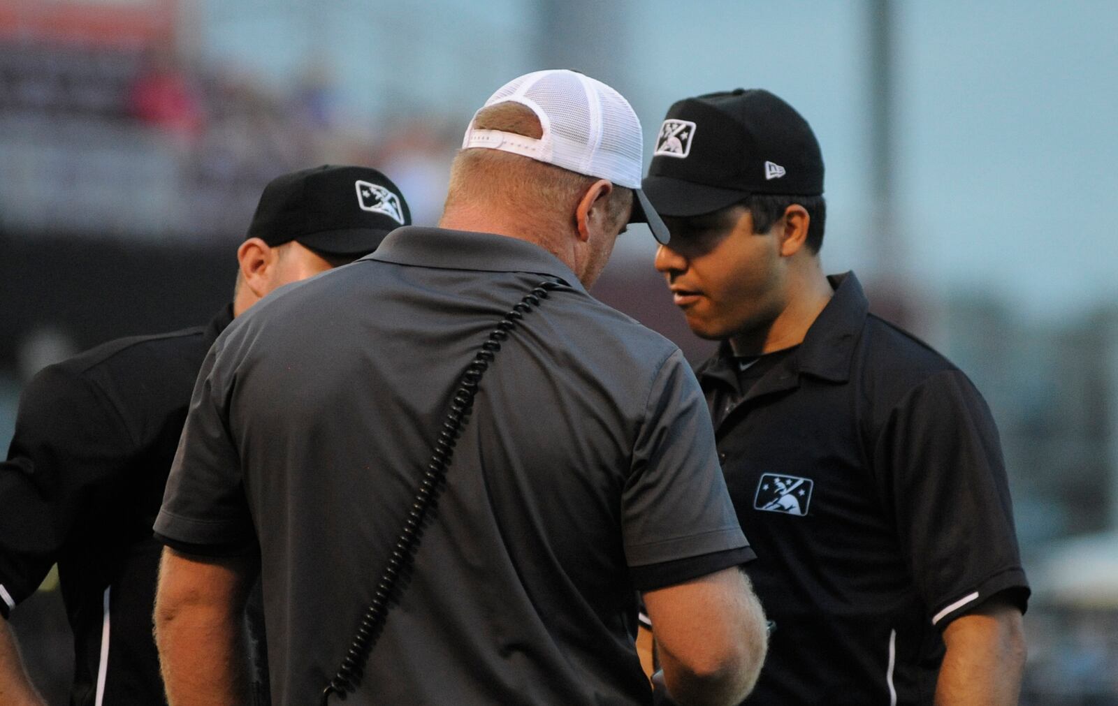 Fifth Third Field and Dragons Sports Turf Manager Britt Barry (middle) huddles with the umpires prior to the game being suspended due to impending rain. MARC PENDLETON / STAFF