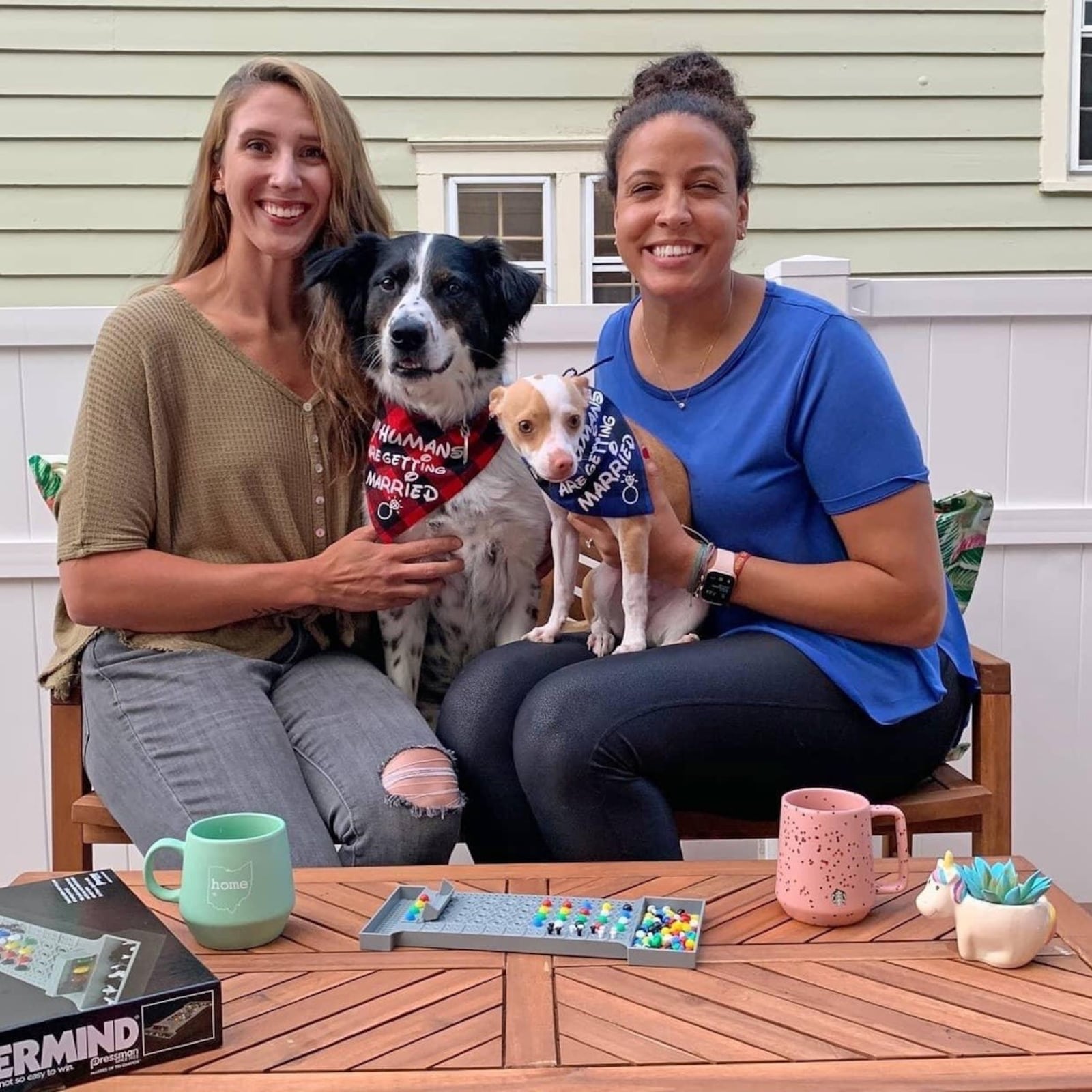 Cassie Sant (left) and Casey Nance and two of their dogs celebrate on the deck of their home in Akron after Casey accepted Cassie’s marriage proposal last August. The couple plans to wed next May 21. CONTRIBUTED