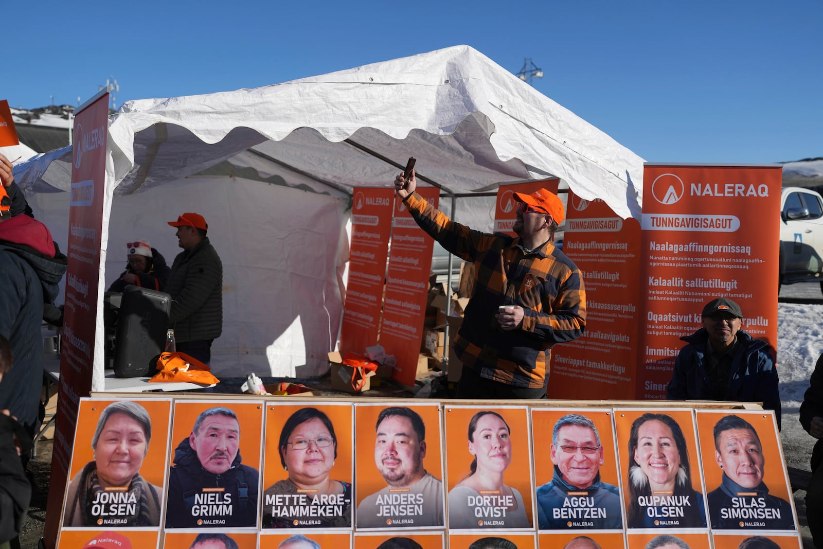 A member of Naleraq party attends a video call outside of a pulling station during parliamentary elections in Nuuk, Greenland, Tuesday, March 11, 2025. (AP Photo/Evgeniy Maloletka)