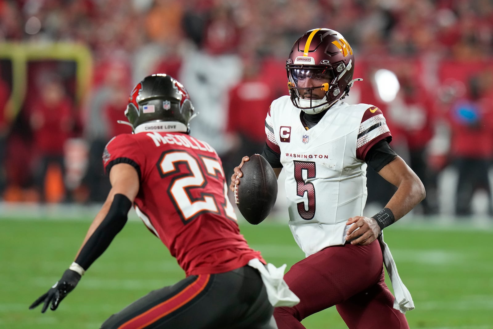 Washington Commanders quarterback Jayden Daniels (5) runs against Tampa Bay Buccaneers cornerback Zyon McCollum (27) during the first half of an NFL wild-card playoff football game in Tampa, Fla., Sunday, Jan. 12, 2025. (AP Photo/Chris O'Meara)