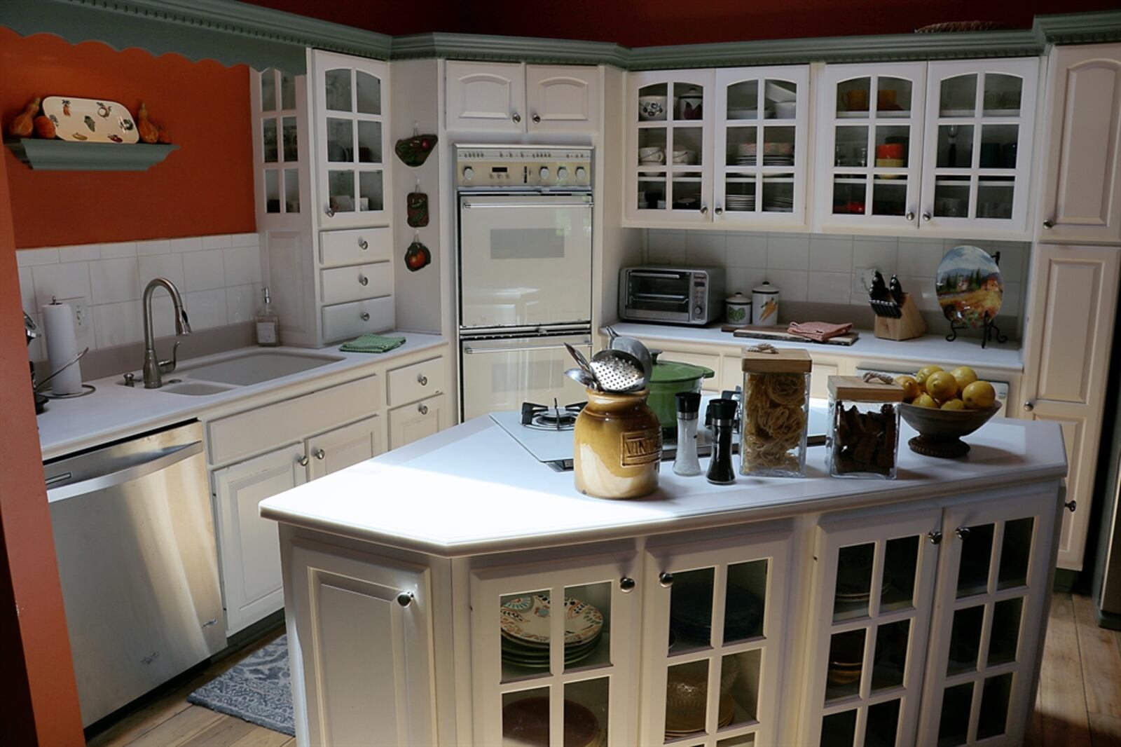 White cabinetry with glass-panel doors fills two walls of the kitchen and surround appliances that include double wall ovens, a dishwasher, a bread warmer, and refrigerator. Drawers and cabinets offer plenty of storage. Solid-surface countertops complement the cabinetry and double sink. CONTRIBUTED PHOTO BY KATHY TYLER