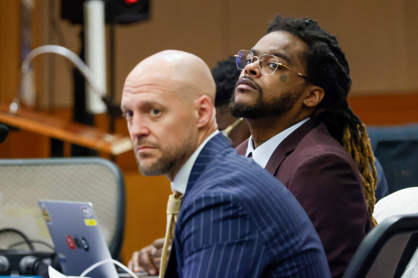 Shannon Stillwell, center back, sits with his attorney, Max Schardt, left, as he looks at the prosecutors during the Young Thug trial at Fulton County Courthouse in Atlanta on Tuesday, Nov. 26, 2024. (Miguel Martinez/Atlanta Journal-Constitution via AP)