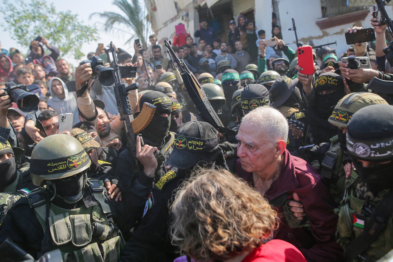 Gadi Moses, 80, center right, who has been held hostage by Hamas in Gaza since October 7, 2023, is escorted by Hamas and Islamic Jihad fighters as she is handed over to the Red Cross in Khan Younis, southern Gaza Strip, Thursday Jan. 13, 2025.(AP Photo/Jehad Alshrafi)