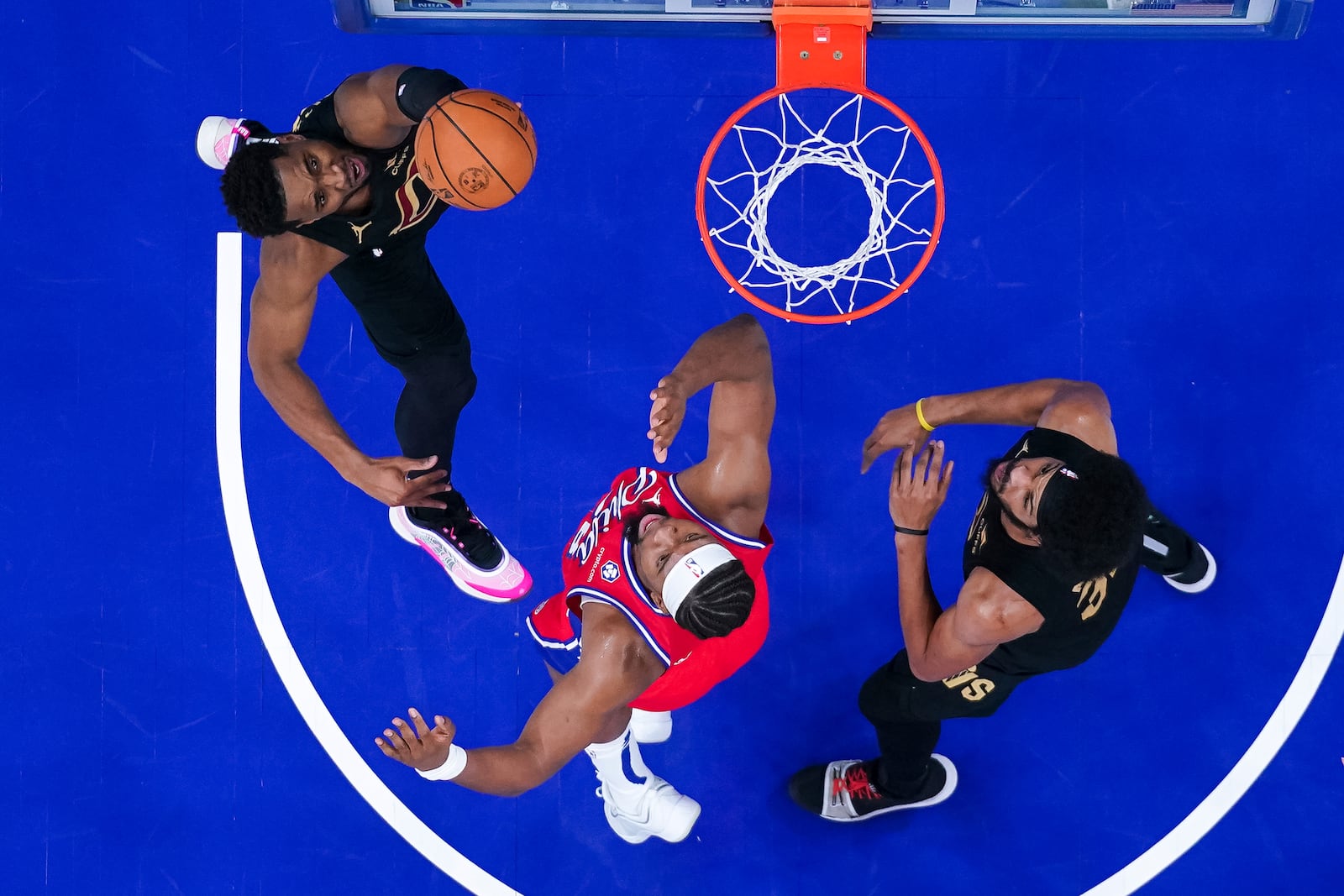 Cleveland Cavaliers' Donovan Mitchell, left, shoots against Philadelphia 76ers' Guerschon Yabusele, center, during the first half of an NBA basketball game, Friday, Jan. 24, 2025, in Philadelphia. (AP Photo/Chris Szagola)