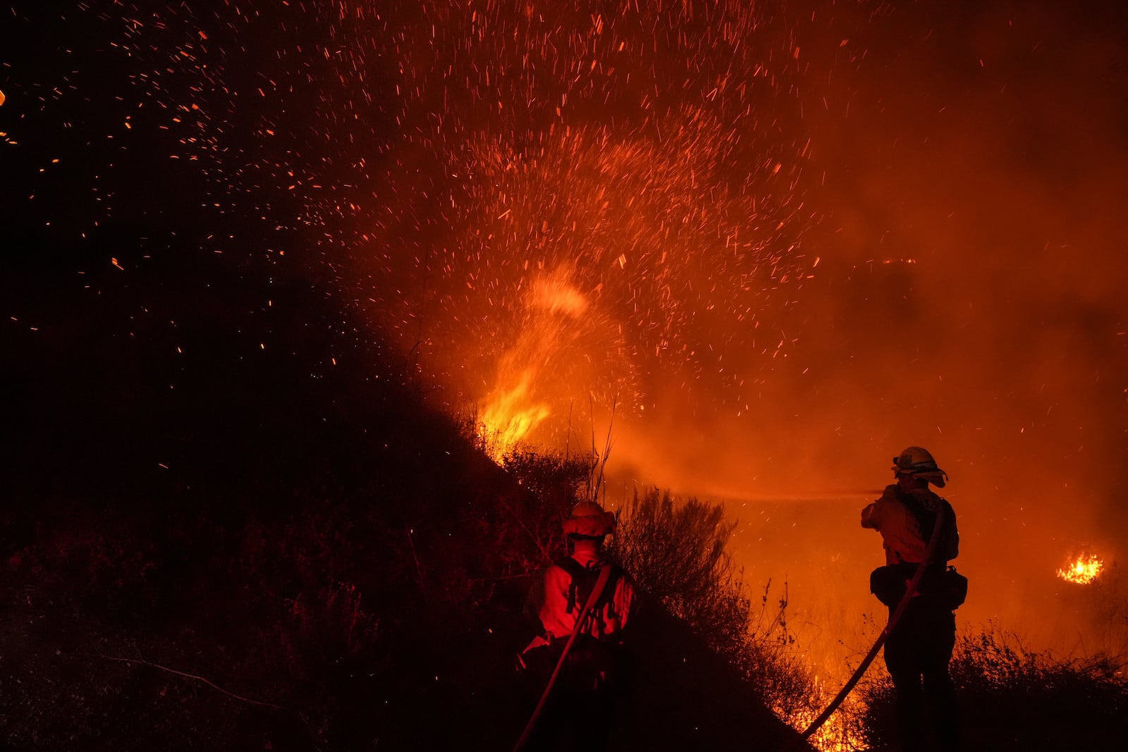 Two firefighters put out flames while battling the Franklin Fire in Malibu, Calif., Tuesday, Dec. 10, 2024. (AP Photo/Jae C. Hong)