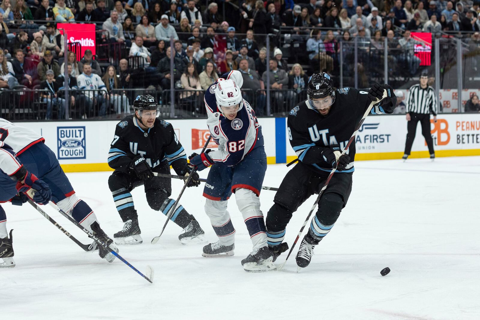 Utah Hockey Club center Nick Schmaltz (8) and center Barrett Hayton (27) go after the puck against Columbus Blue Jackets left wing Mikael Pyyhtia (82) during the first period of an NHL hockey game Friday, Jan. 31, 2025, in Salt Lake City. (AP Photo/Melissa Majchrzak)