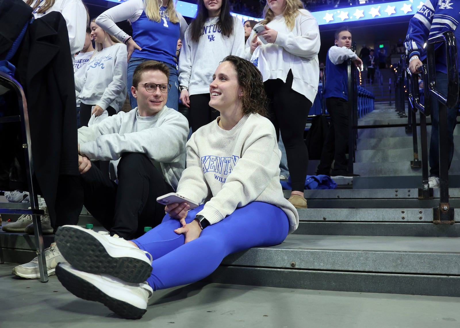 Daniel Peterson, left, and his girlfriend Sydni Reeling, right, sit on the floor before an NCAA college basketball game between Kentucky and Louisville in Lexington, Ky., Saturday, Dec. 14, 2024. (AP Photo/James Crisp)