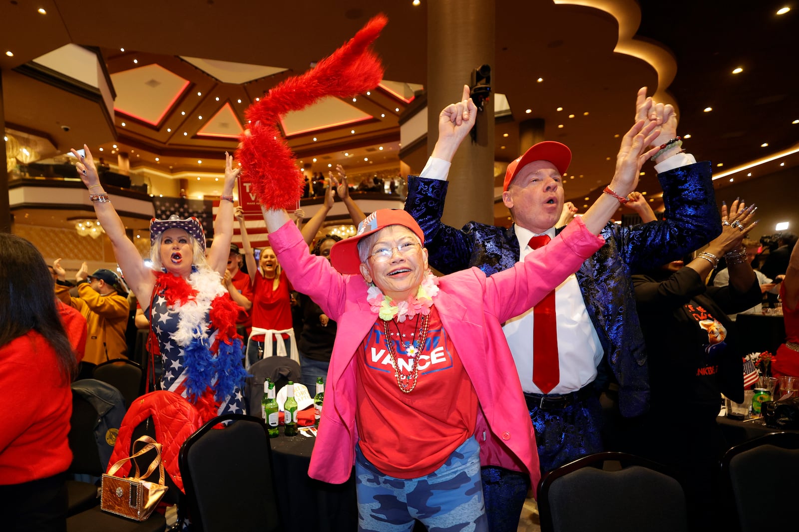 Supporters of Republican presidential nominee former President Donald Trump, Stephanie Smith, left, Sandi Steinbeck, center, and Thomas Brewer, right, cheer as Fox News calls the election for Trump during a GOP election watch party at the Ahern Hotel, Tuesday, Nov. 5, 2024, in Las Vegas. (Steve Marcus/Las Vegas Sun via AP)