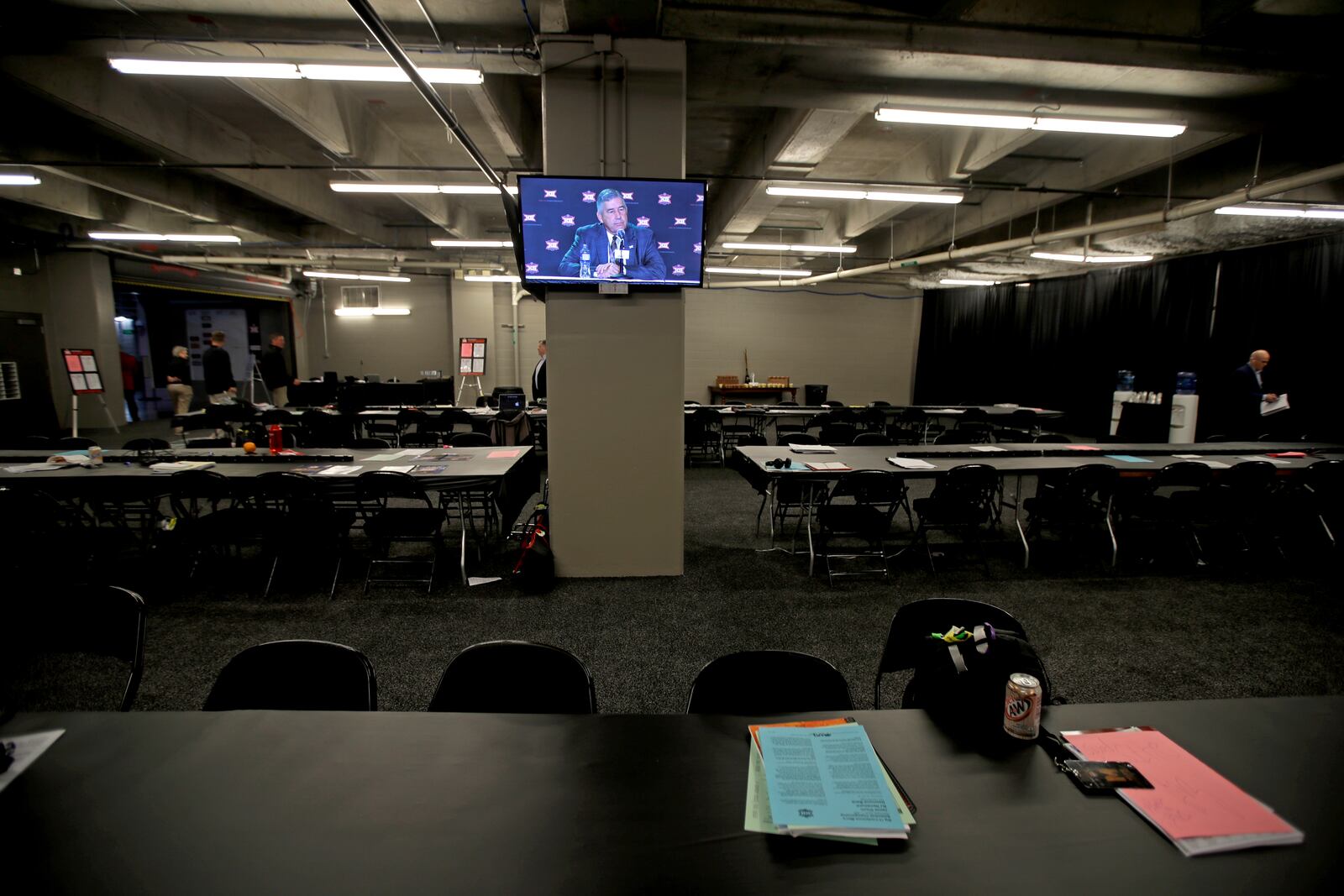 FILE - Big 12 commissioner Bob Bowlsby is displayed on a monitor in an empty media room as he talks to the media after canceling the remaining NCAA college basketball games in the Big 12 Conference tournament due to concerns about the coronavirus, Thursday, March 12, 2020, in Kansas City, Mo. (AP Photo/Charlie Riedel, File)