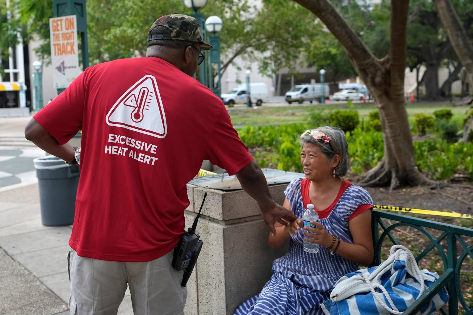 FILE - Ricky Leath, an outreach specialist with the City of Miami, talks with Bei Zhao, right, as he works with the Miami-Dade County Homeless Trust to distribute bottles of water and other supplies to the homeless population, helping them manage high temperatures, May 15, 2024, in Miami. (AP Photo/Lynne Sladky, File)