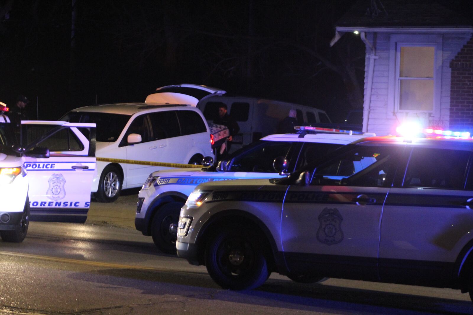 A Montgomery County Coroner's worker loads a body on a stretcher into an unmarked van after three people were found dead in a shooting inside a house in the 2600 block of North Gettysburg Avenue in Dayton.