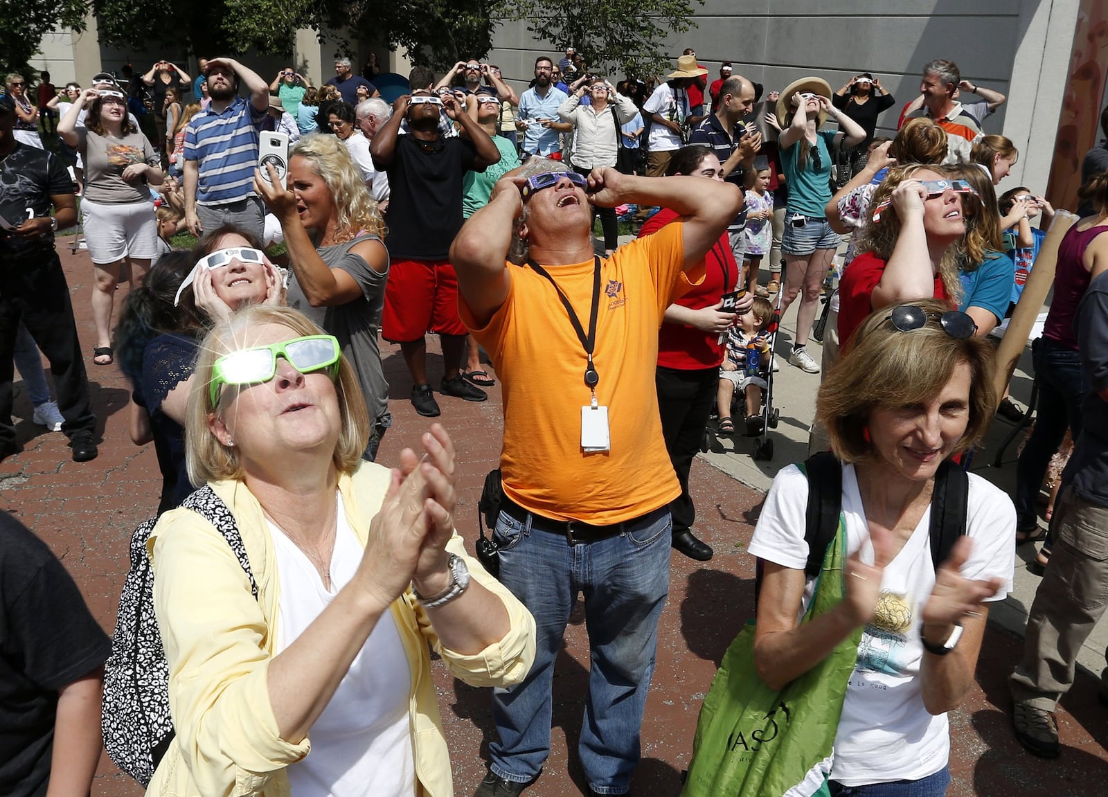 A crowd at the Boonshoft Museum of Discovery applauds as the solar eclipse reaches its maximum coverage in this region. LISA POWELL/STAFF 