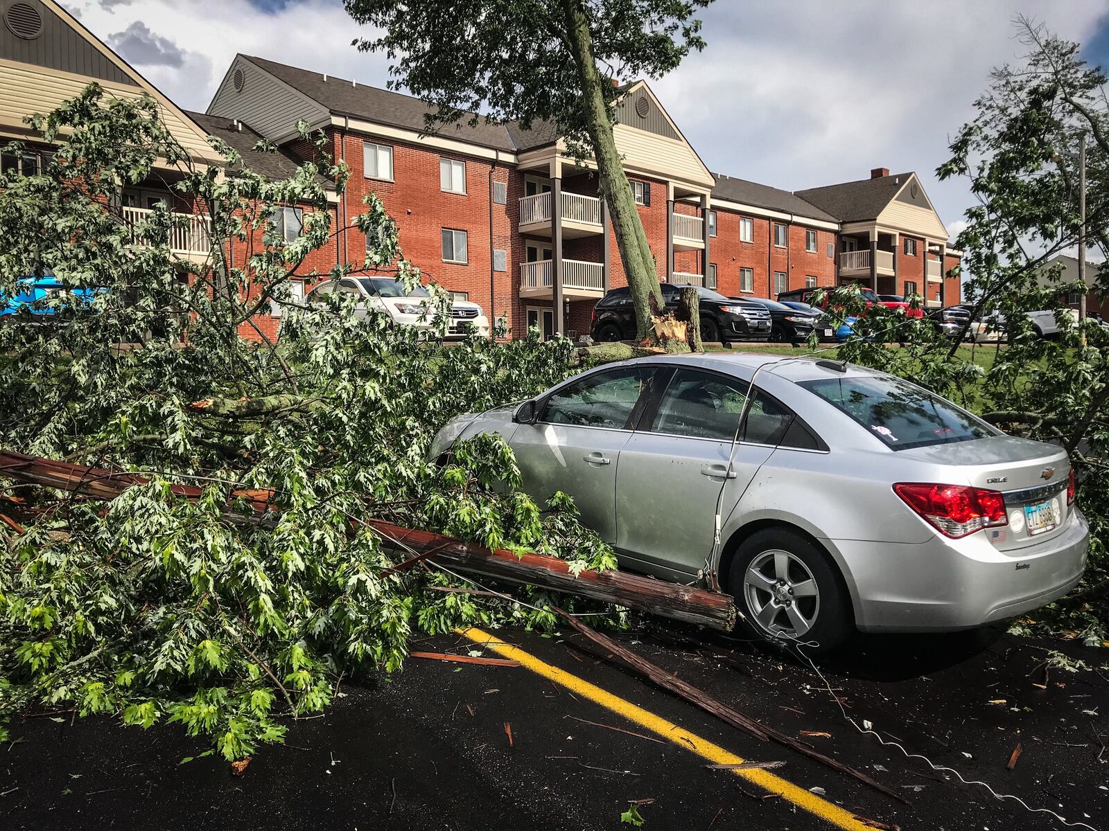 A tree knocks down two power poles at an apartment complex off Gracemore Avenue in Kettering during a strong storm late Wednesday afternoon, June 10, 2020. JIM NOELKER / STAFF