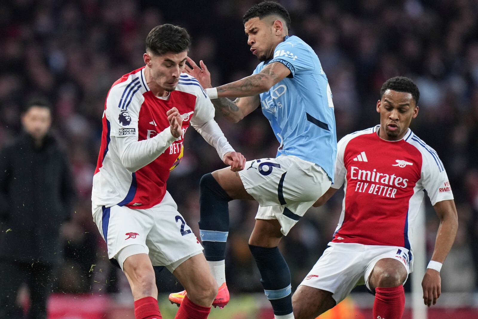 Manchester City's Savinho, center, and Arsenal's Kai Havertz, left, fight for the ball during the English Premier League soccer match between Arsenal and Manchester City at the Emirates stadium in London, Sunday, Feb. 2, 2025. (AP Photo/Alastair Grant)