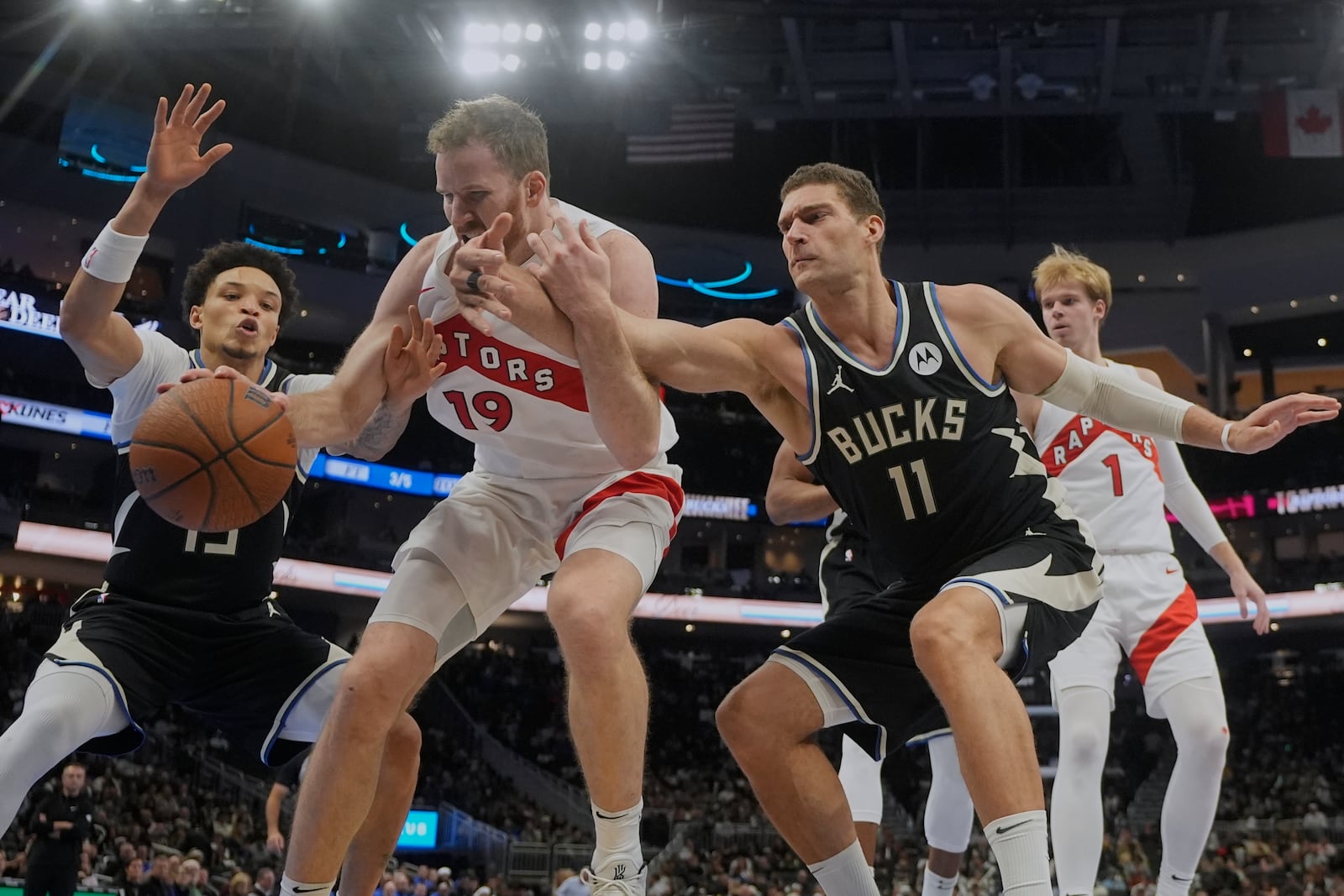 Toronto Raptors' Jakob Poeltl goes after a loose ball with Milwaukee Bucks' Brook Lopez and Ryan Rollins during the second half of an Emirates NBA Cup tournament basketball game Tuesday, Nov. 12, 2024, in Milwaukee. (AP Photo/Morry Gash)