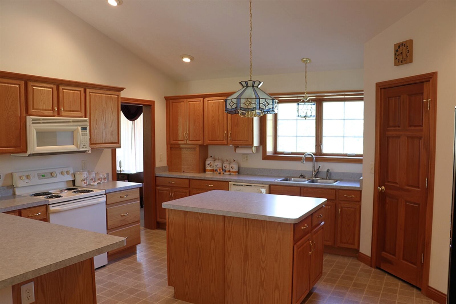 In the kitchen, a sink is below a front-facing window and oak cabinetry wraps around the appliances.