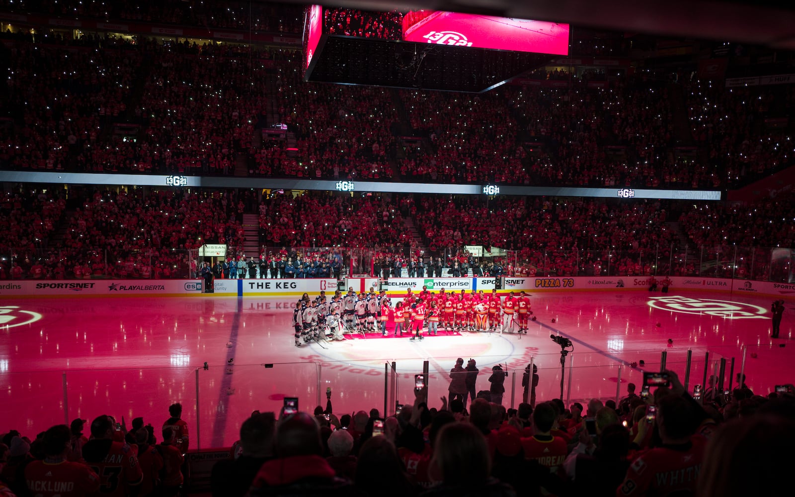 Columbus Blue Jackets players and Calgary Flames players join the family of Johnny Gaudreau at centre ice prior to first period NHL hockey action in Calgary on Tuesday, Dec. 3, 2024.THE CANADIAN PRESS/Jeff McIntosh/The Canadian Press via AP)