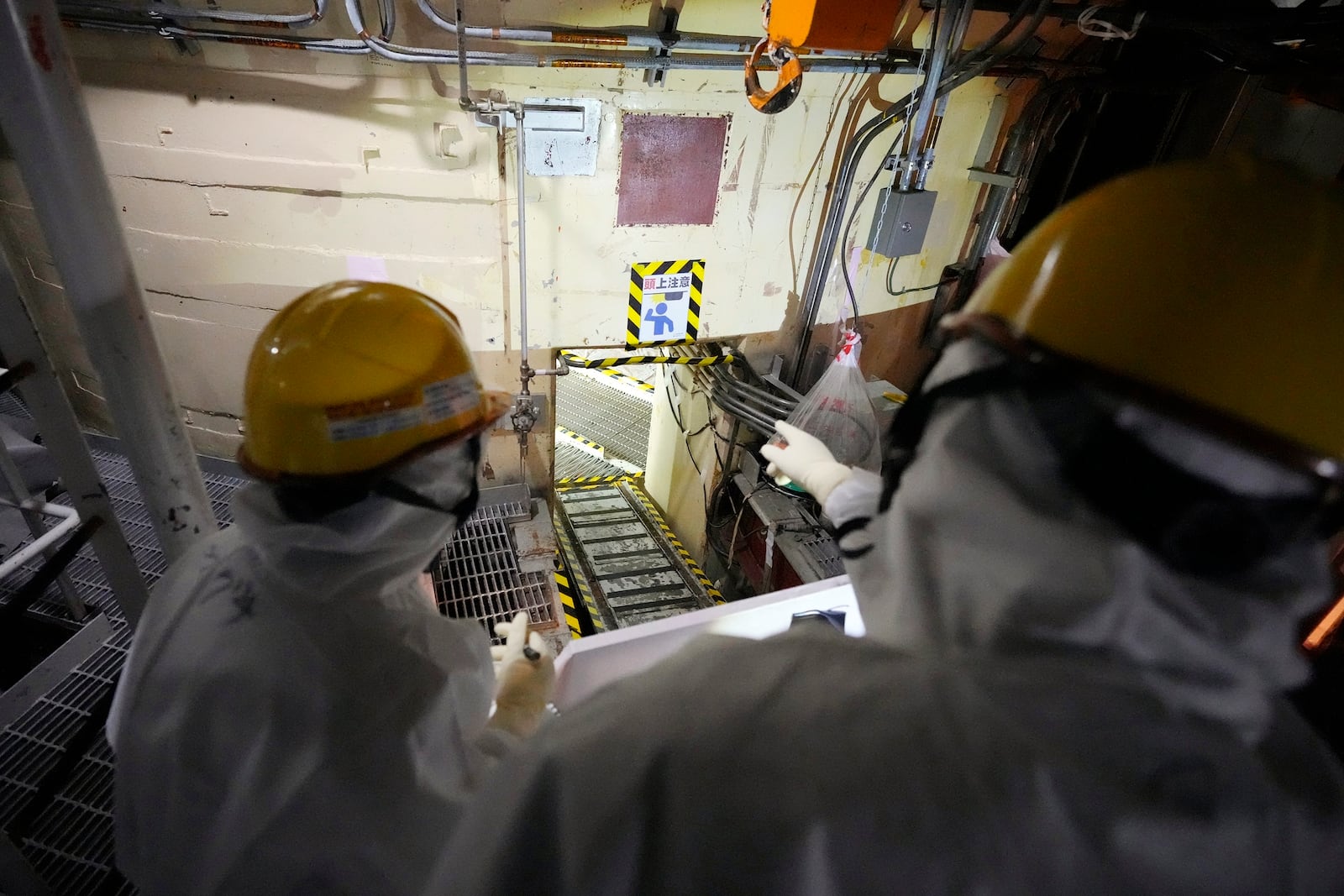 Employees of Tokyo Electric Power Company Holdings (TEPCO) take AP journalists to the area under the Unit 5 reactor pressure vessel, which survived the earthquake-triggered tsunami in 2011, at the Fukushima Daiichi nuclear power plant in Futaba town, northeastern Japan, on Monday Feb. 20, 2025. (AP Photo/Eugene Hoshiko)