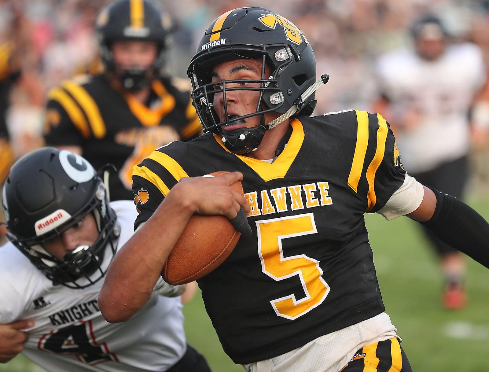 Shawnee quarterback Robie Glass avoids a tackle by Greenon’s Arlie Benson as he carries the ball for a first down during Friday’s season opener. BILL LACKEY/STAFF