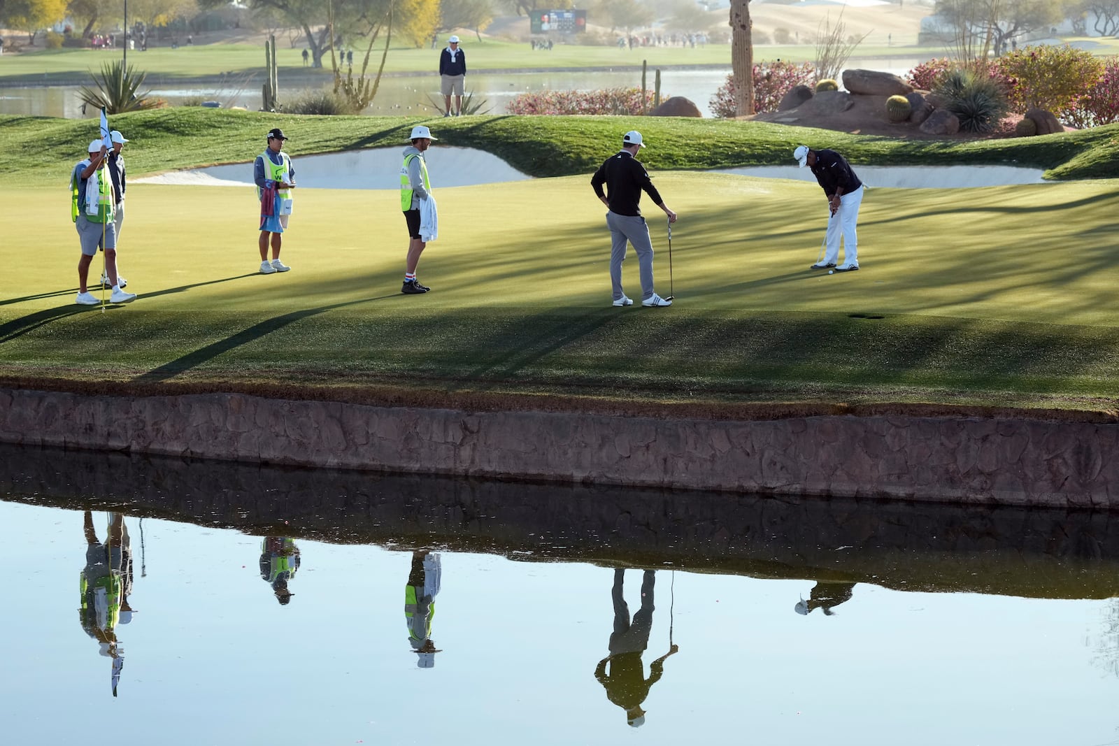 Hideki Matsuyama, right, of Japan, hits a putt on the 12th green as Nick Taylor, second from right, of Canada, looks on during the first round of the Waste Management Phoenix Open PGA Tour golf tournament at the TPC Scottsdale Thursday, Feb. 6, 2025, in Scottsdale, Ariz. (AP Photo/Ross D. Franklin)