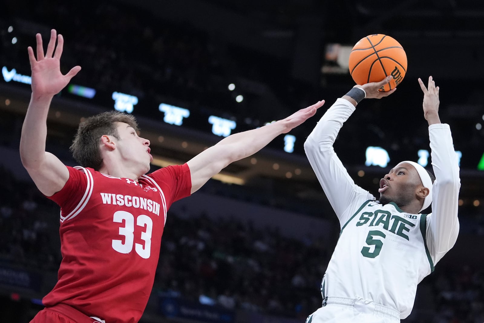 Michigan State guard Tre Holloman (5) shoots on Wisconsin guard Jack Janicki (33) during the first half of an NCAA college basketball game in the semifinals of the Big Ten Conference tournament in Indianapolis, Saturday, March 15, 2025. (AP Photo/Michael Conroy)