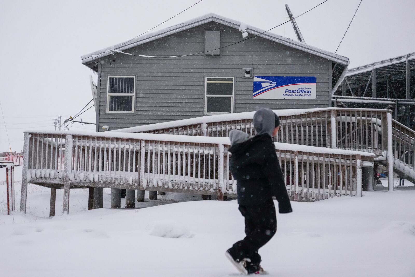 A resident walks with their child past the village's post office in Kaktovik, Alaska, Wednesday, Oct. 16, 2024. (AP Photo/Lindsey Wasson)