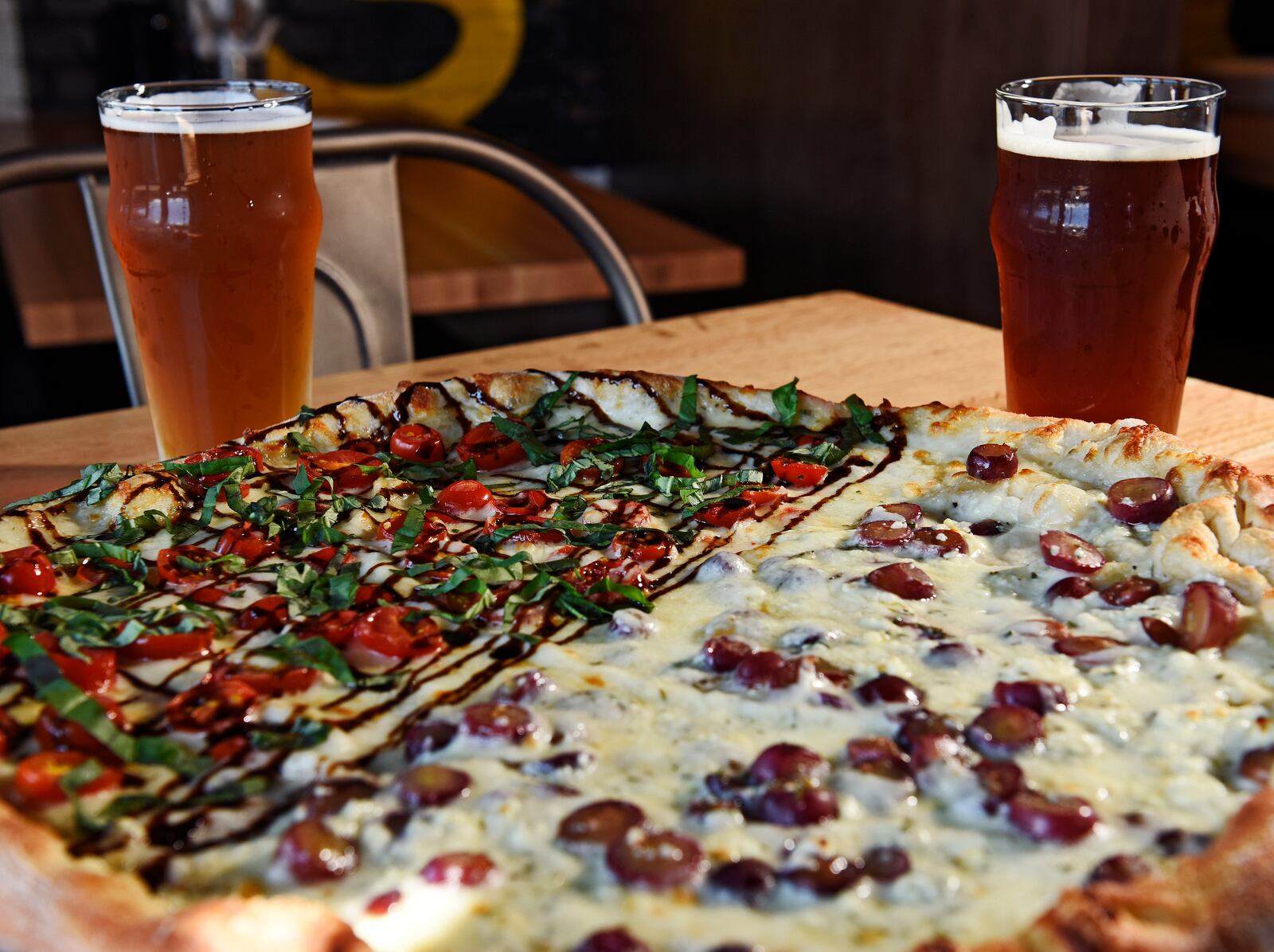 This Pies & Pints pizza is half Mozzarella Caprese with fresh mozzarella, tomatoes, basil and a balsamic reduction and half Grape & Gorgonzola with red grapes, gorgonzola and fresh rosemary. NICK GRAHAM/STAFF