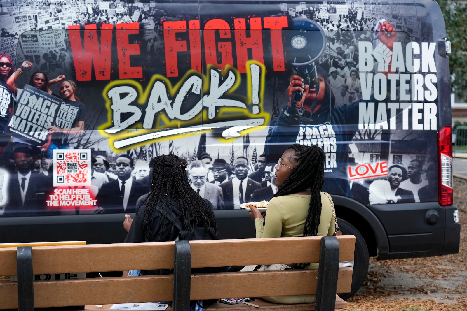 Students eat a snack by a van encouraging students to vote during a get out the vote rally at North Carolina A&T in Greensboro, N.C., Monday, Oct. 28, 2024. (AP Photo/Chuck Burton)