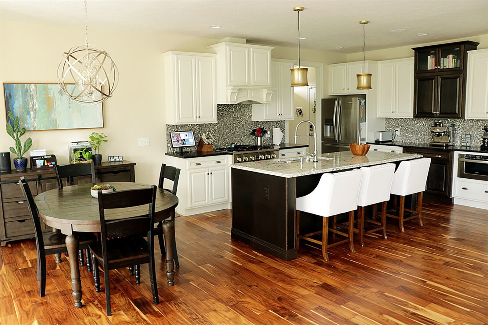 An island divides the kitchen from the great room and offers seating for four and has a double sink and dishwasher within the kitchen work area. White cabinetry has a couple of contrasting brown accents and granite countertops provide plenty of space. CONTRIBUTED PHOTO BY KATHY TYLER