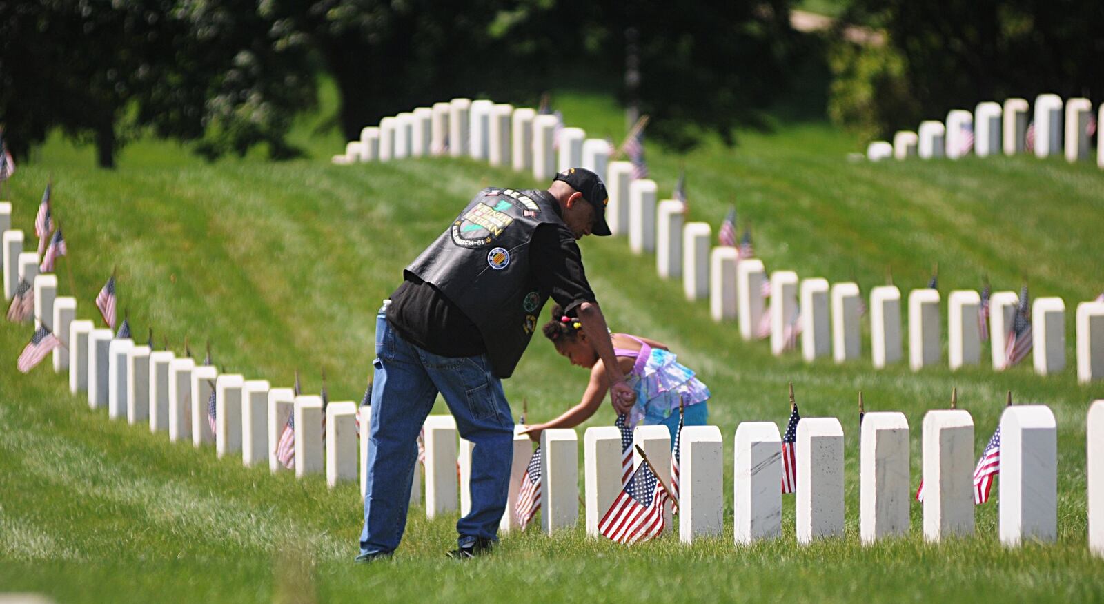 Army retired major Gary S. Conley gets help from his granddaughter, Kailynne Conley, 4, straightening flags at the Dayton National Cemetery on Memorial Day, May 30, 2016.