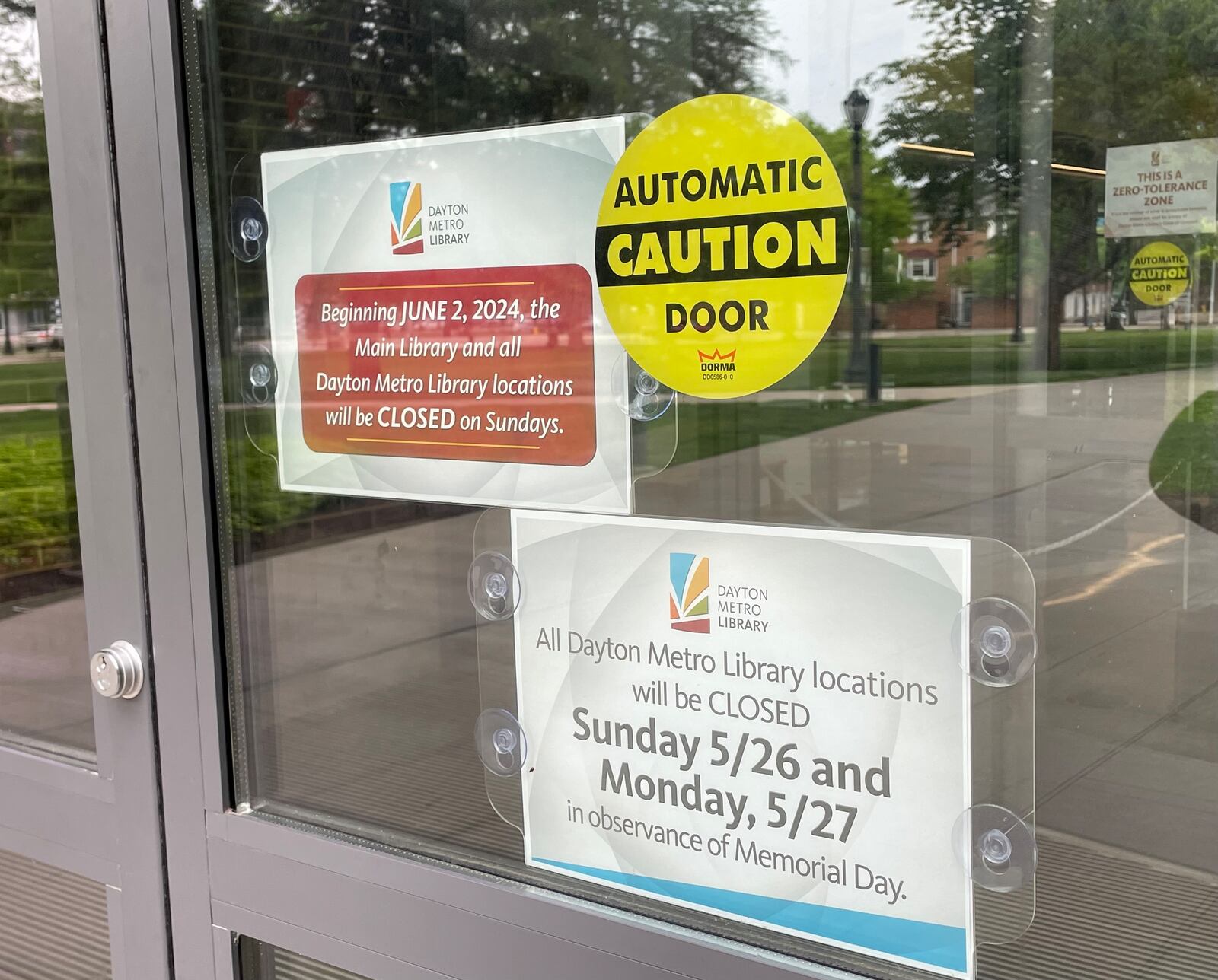 Signs have been posted on entrances of Dayton Metro Library's main branch in downtown Dayton to remind patrons of the new schedule for the location.