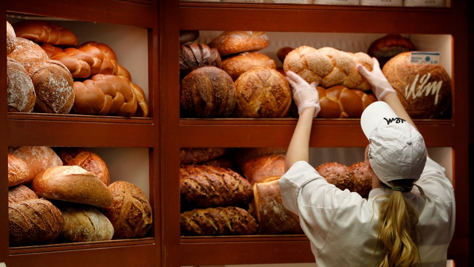 Cara Andres, retail bakery associate at Dorothy Lane Market, arranges over a dozen varieties of bread at the Washington Twp. store. LISA POWELL / STAFF