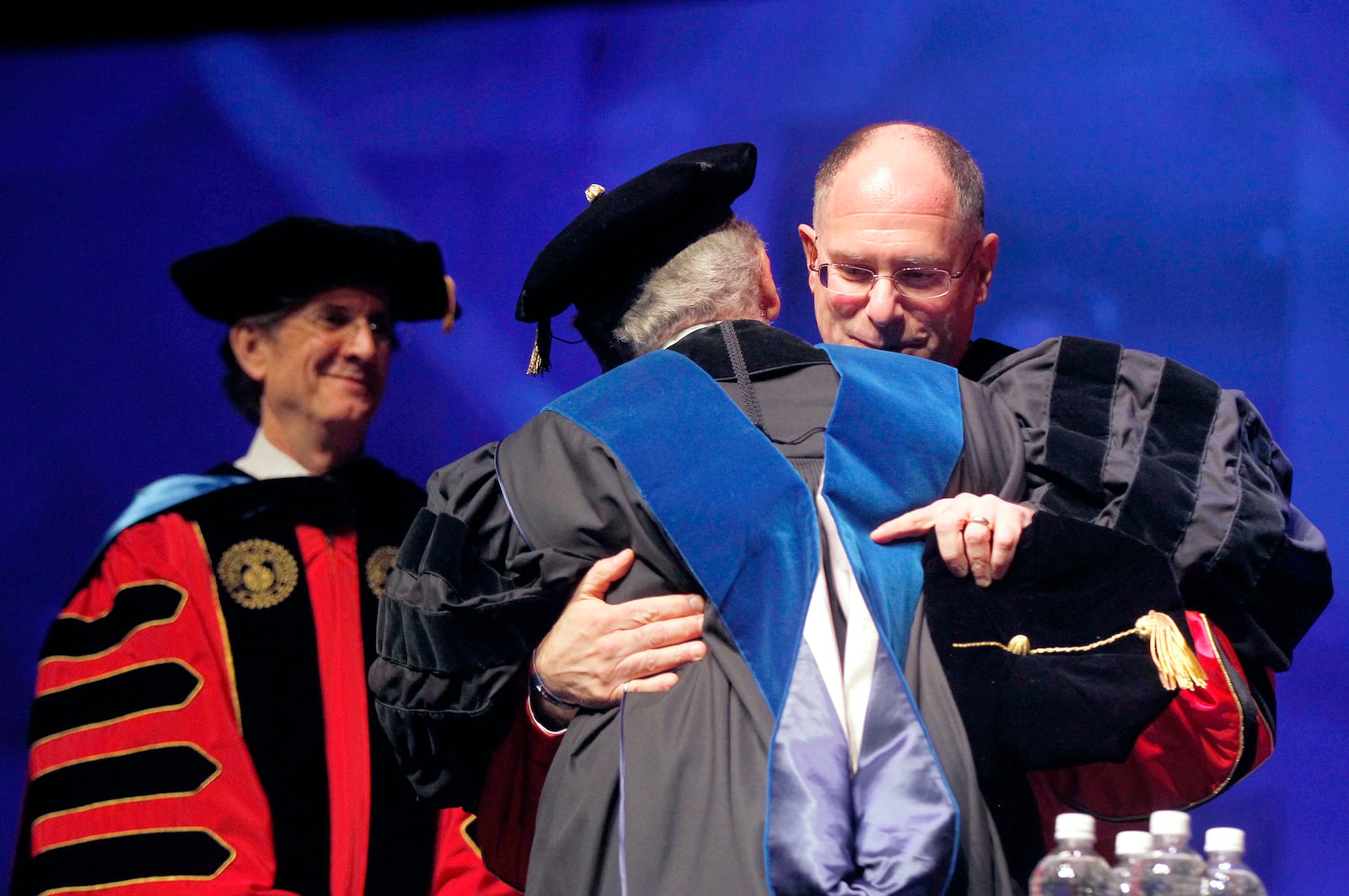 The installation for Eric F. Spina, the 19th president of the  University of Dayton, was held at UD Arena Tuesday. Spina, embracing Brother Raymond Fitz who was president until 2002, became UD's president July 1, 2016 and succeeds Daniel J. Curran (left).   LISA POWELL / STAFF