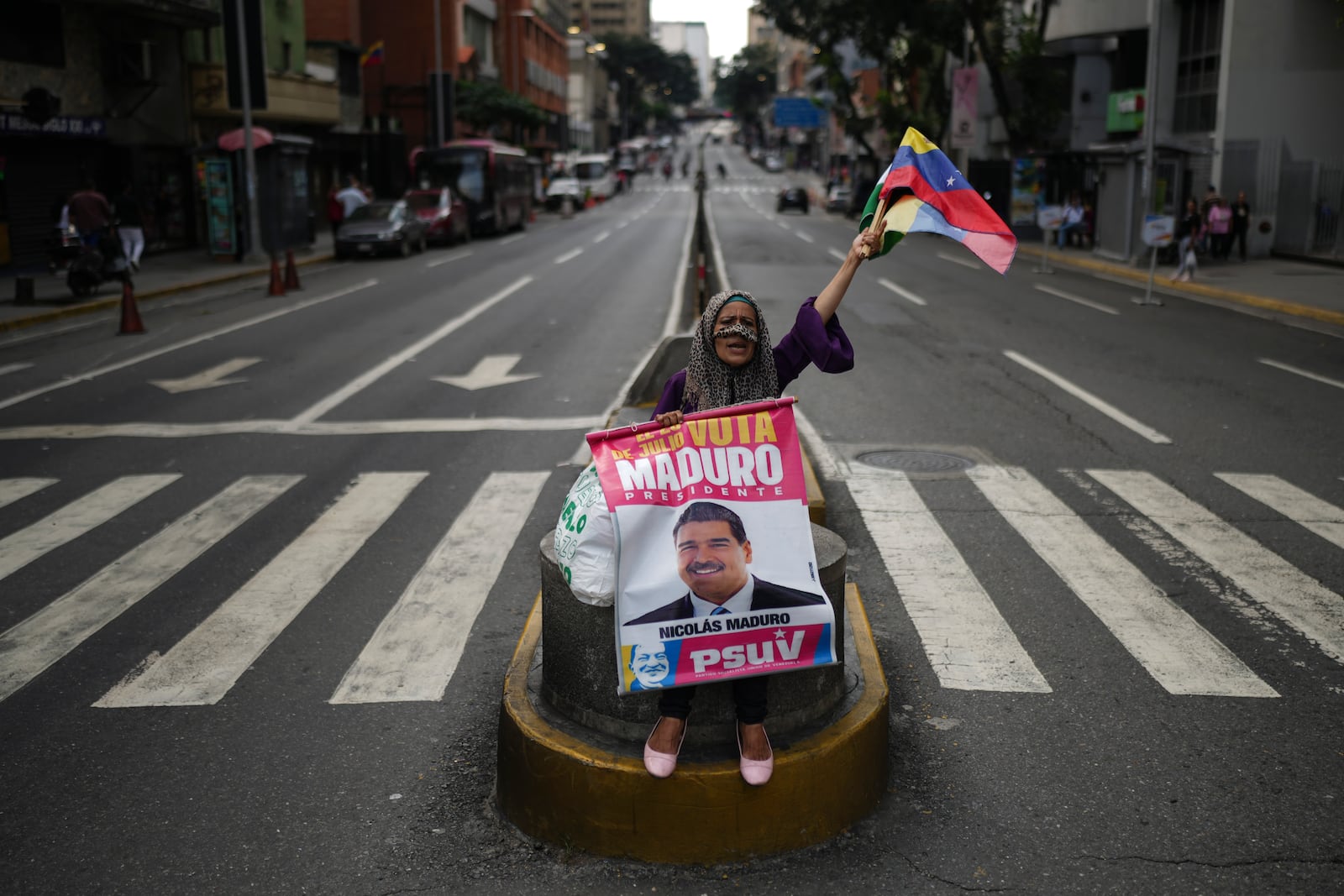 A government supporter holds a poster of President Nicolas Maduro in the middle of a street in Caracas, Venezuela, Thursday, Nov. 21, 2024. (AP Photo/Ariana Cubillos)