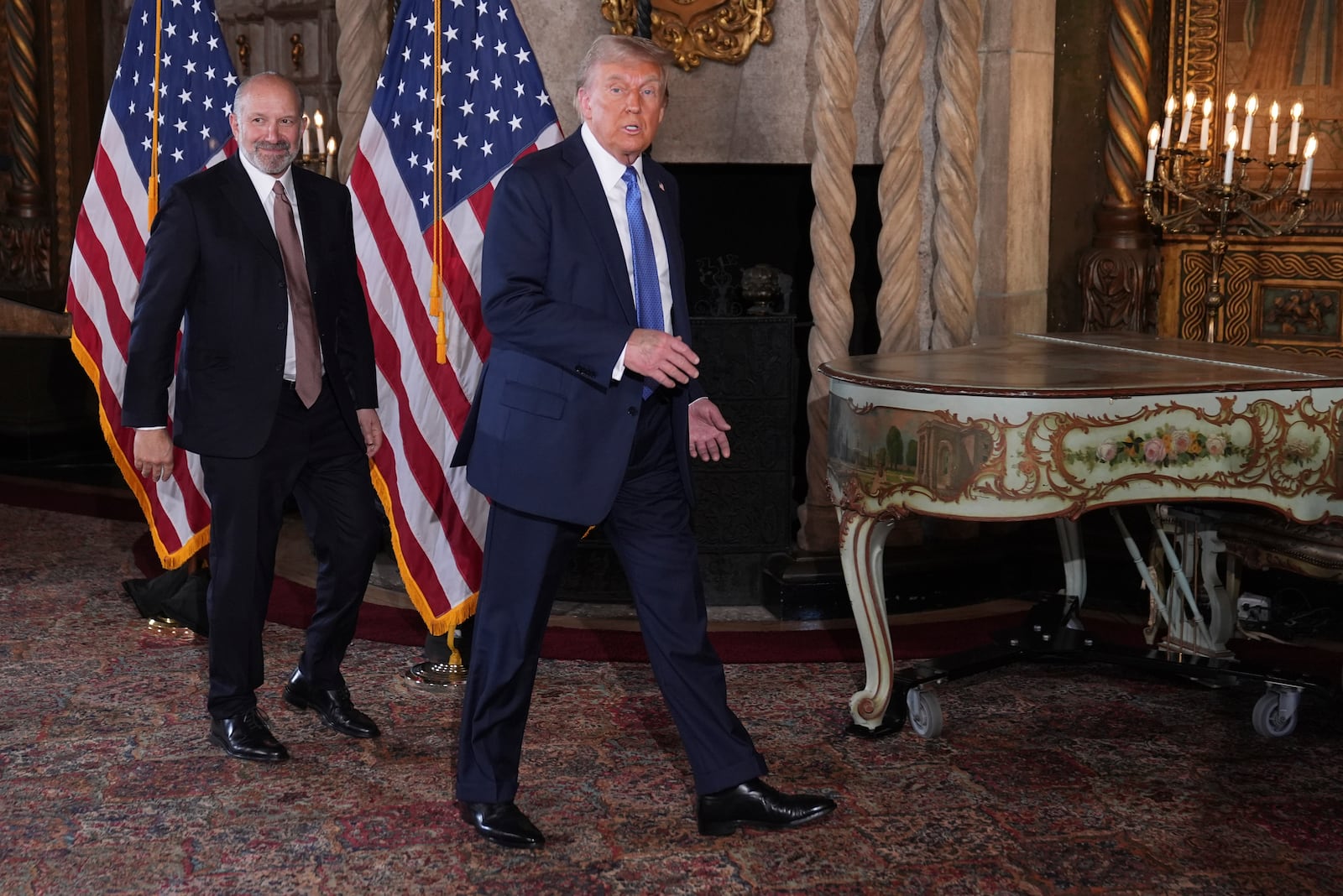 President-elect Donald Trump departs a news conference at Mar-a-Lago, Monday, Dec. 16, 2024, in Palm Beach, Fla., followed by Commerce Secretary nominee Howard Lutnick. (AP Photo/Evan Vucci)