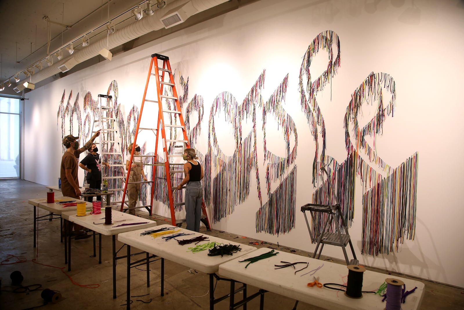 Volunteers hang thousands of shoelaces at The Contemporary Dayton Wednesday to create We The People, a 50-foot-wide wall installation designed by artist Nari Ward. The installation pairs humble of materials (shoelaces) with one of the country’s most lofty and enduring ideas—the U.S. Constitution, according to a release. The artwork will be on display through Nov. 30. The Co has also partnered with the League of Women Voters of the Greater Dayton Area to transform a portion of the gallery into a voter registration center.  LISA POWELL / STAFF