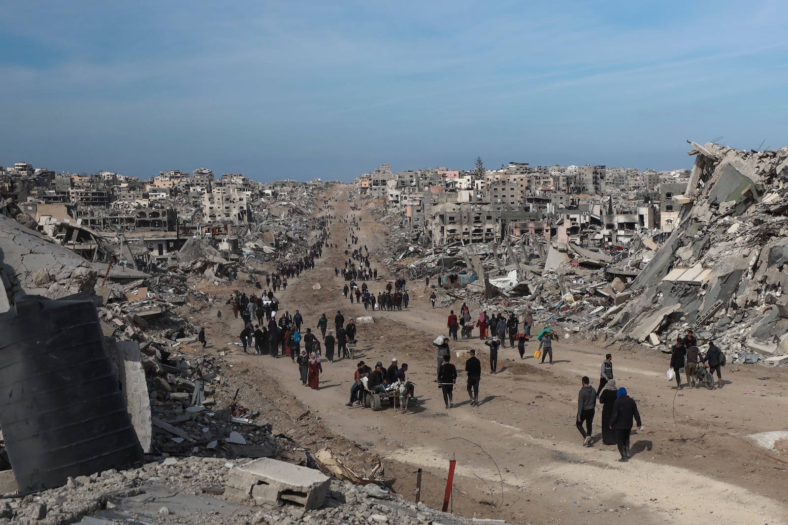 Palestinians walk through the destruction caused by the Israeli air and ground offensive in Jabaliya, as a ceasefire deal between Israel and Hamas went into effect, Sunday, Jan. 19, 2025. (AP Photo/Abed Hajjar)