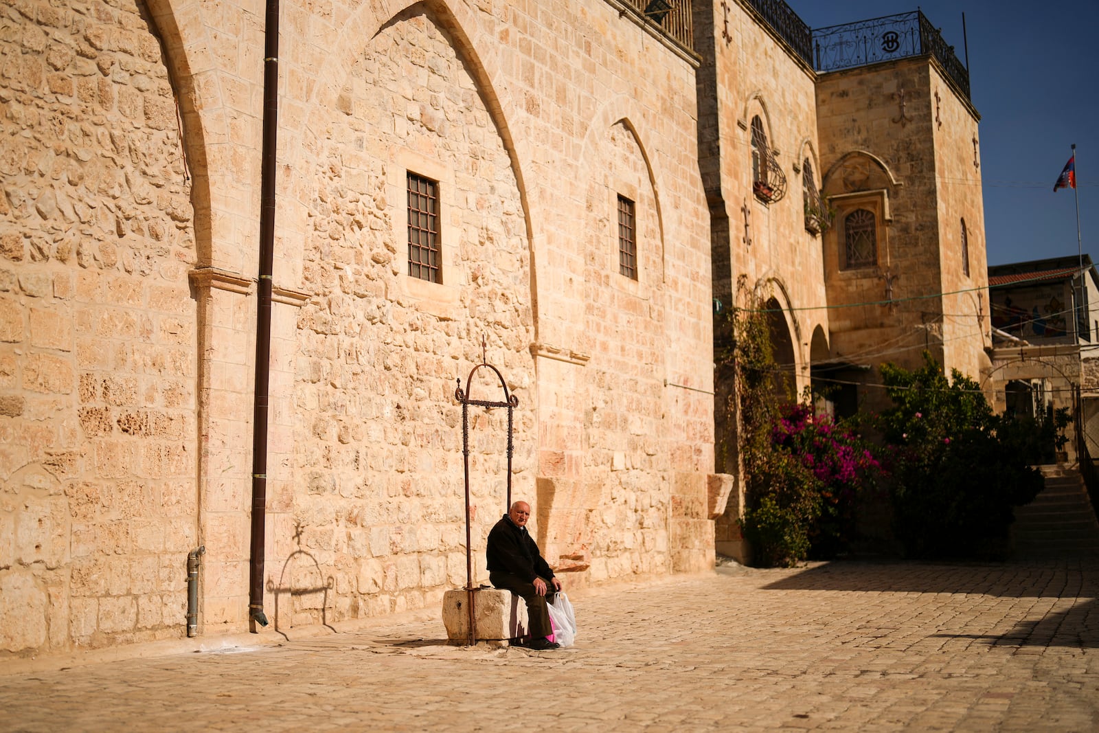 An Armenian resident sits at the main square of the Armenian quarter in Jerusalem, Thursday, Nov. 21, 2024. (AP Photo/Francisco Seco)