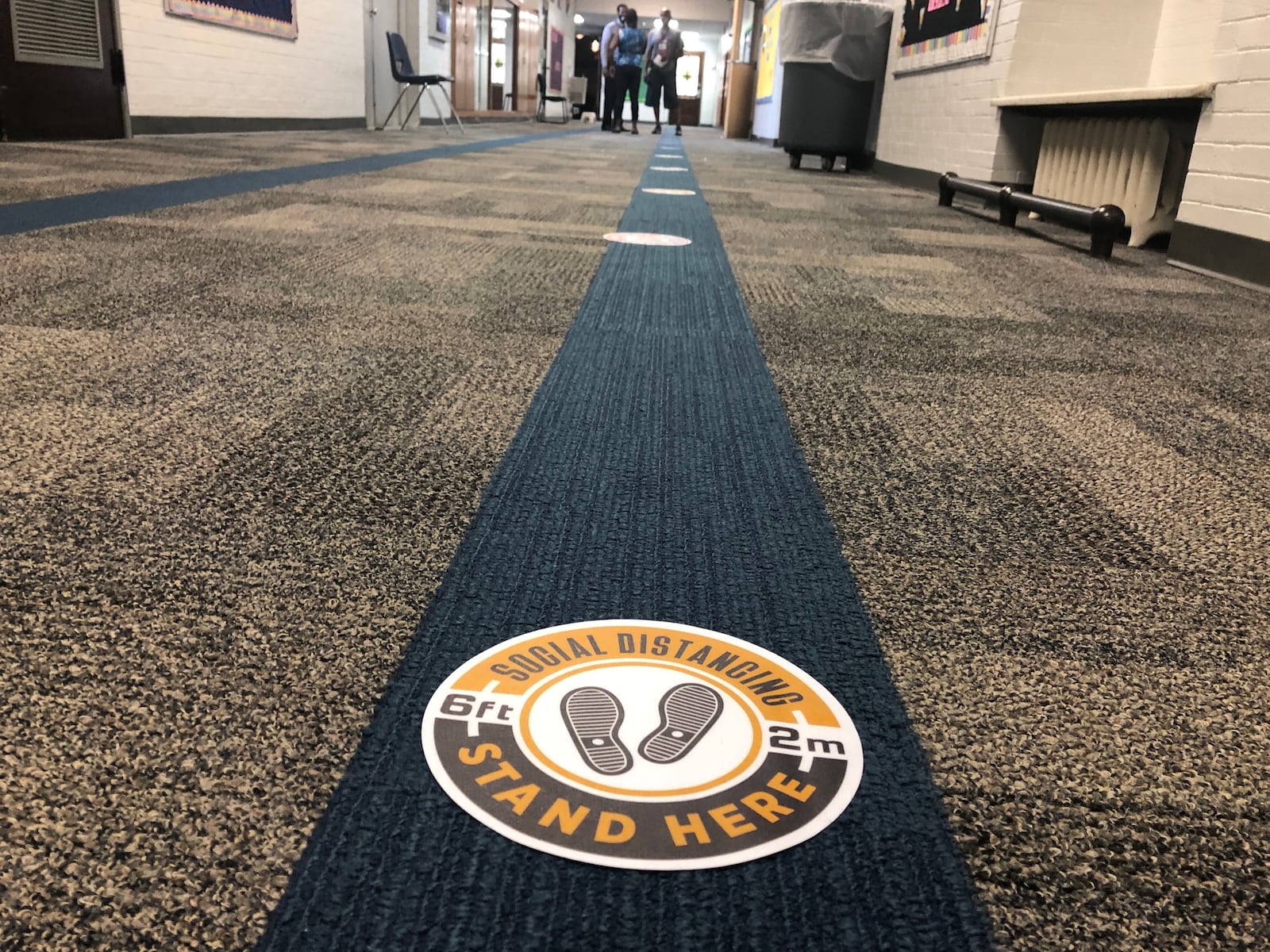 Stickers on the hallway floor at Dayton's Emerson Academy remind staff to observe social distancing protocols on the first day of online classes Wednesday, Aug. 12, 2020.