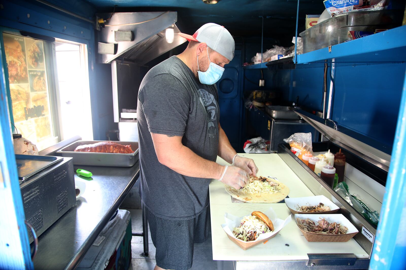 Caption: Scott Green dishes up food in the Dayton Urban BBQ food truck. It is known for smoked ribs, pulled pork and chicken and flavorful wraps. LISA POWELL / STAFF