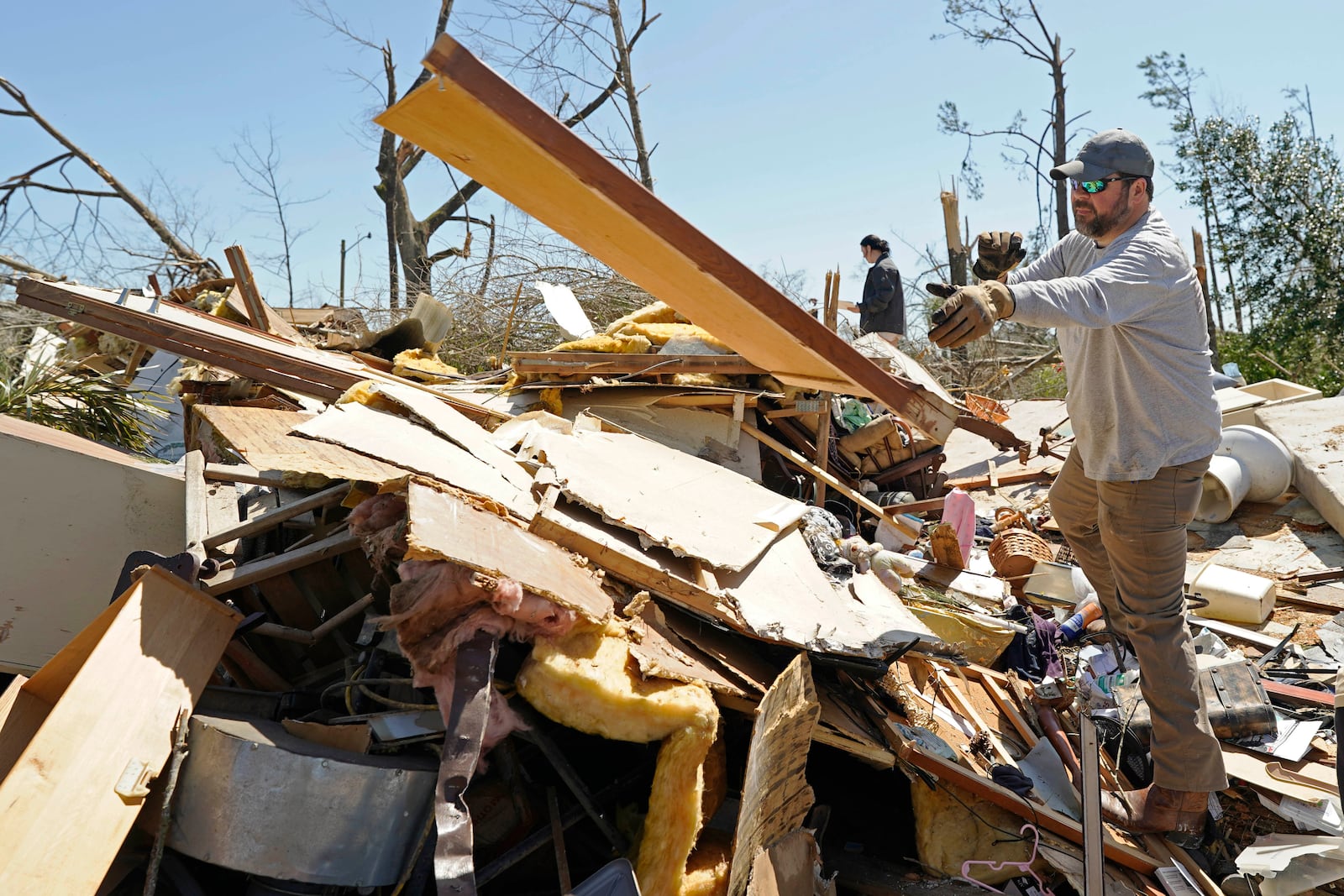 Tommy May, tosses paneling from a tornado destroyed home of relatives, Sunday, March 16, 2025, in Tylertown, Miss. (AP Photo/Rogelio V. Solis)