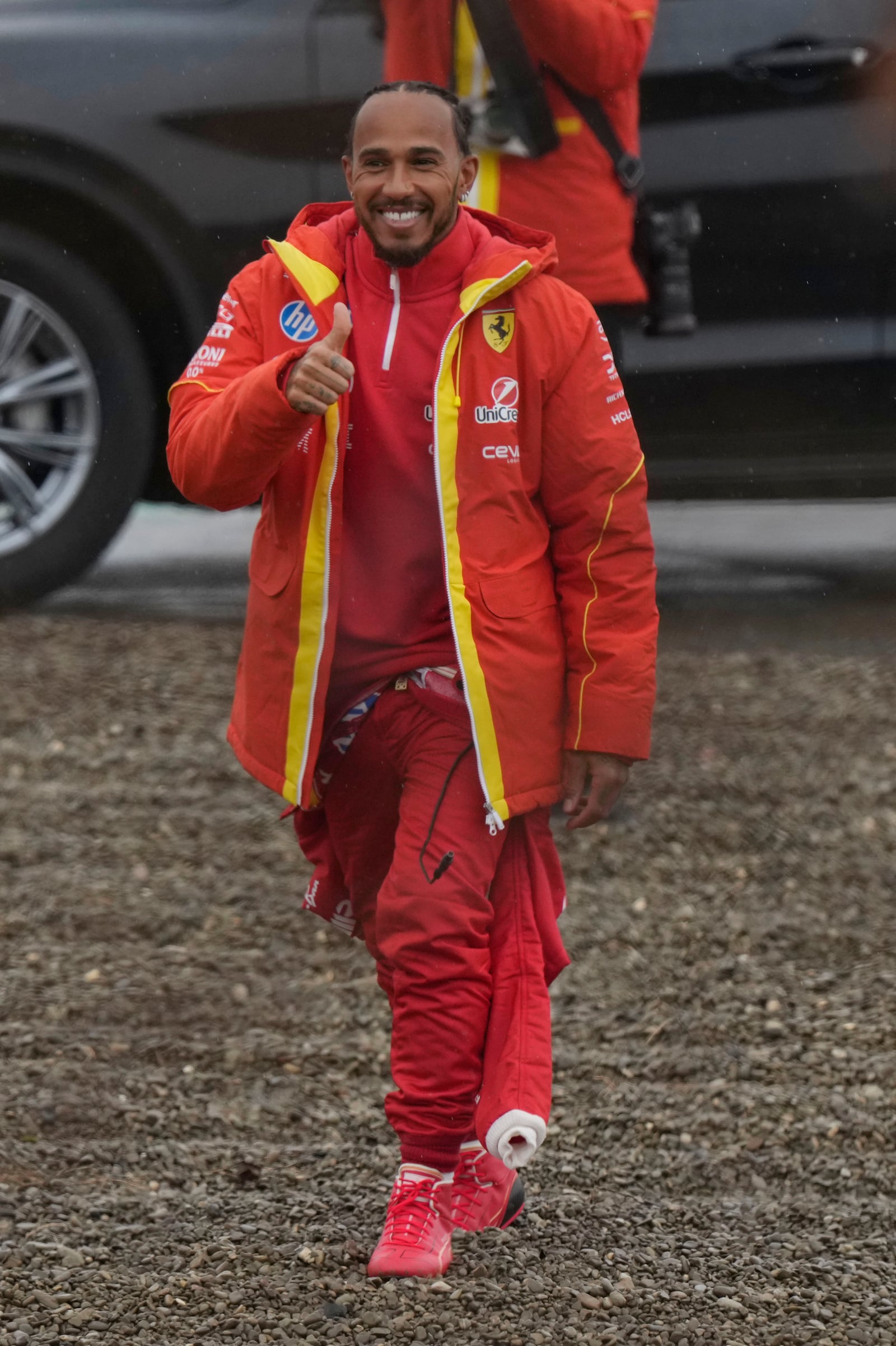 British driver Lewis Hamilton cheers Ferrari fans gathered outside the track, after testing a Ferrari Formula One SF-23, in Fiorano Modenese, Italy, Wednesday, Jan.22, 2025. (AP Photo/Luca Bruno)