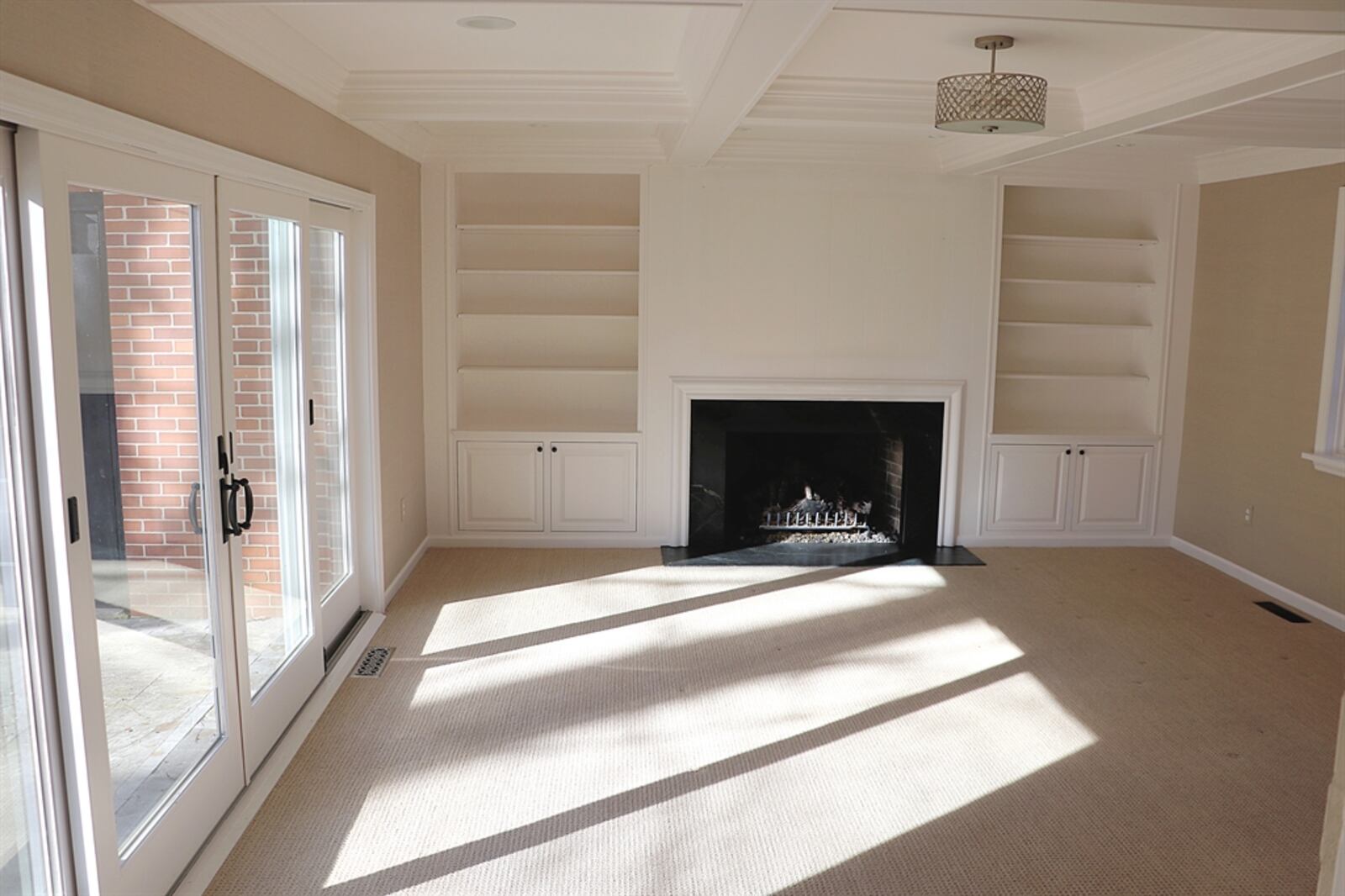 Bookcases and cabinets flank the fireplace in the family room. Large sliding doors open to the backyard paver-stone patio.