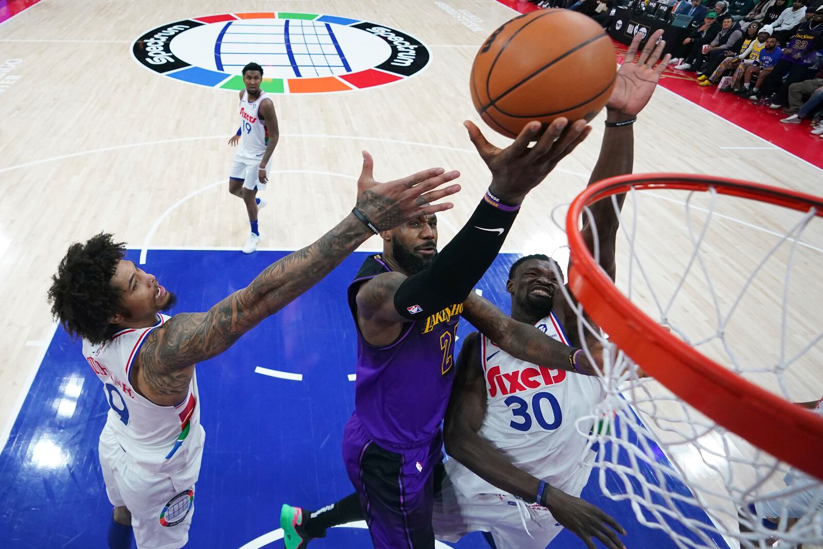 Los Angeles Lakers' LeBron James, center, goes up for a shot between Philadelphia 76ers' Kelly Oubre Jr., left, and Adem Bona during the second half of an NBA basketball game, Tuesday, Jan. 28, 2025, in Philadelphia. (AP Photo/Matt Slocum)