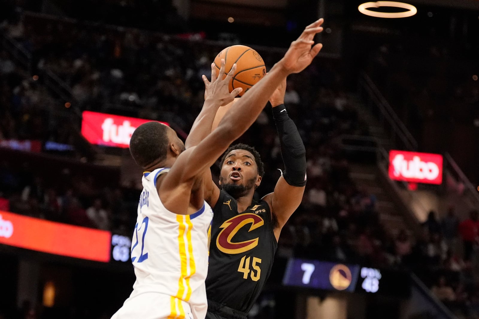 Cleveland Cavaliers guard Donovan Mitchell (45) shoots as Golden State Warriors forward Andrew Wiggins, left, defends in the second half of an NBA basketball game, Friday, Nov. 8, 2024, in Cleveland. (AP Photo/Sue Ogrocki)