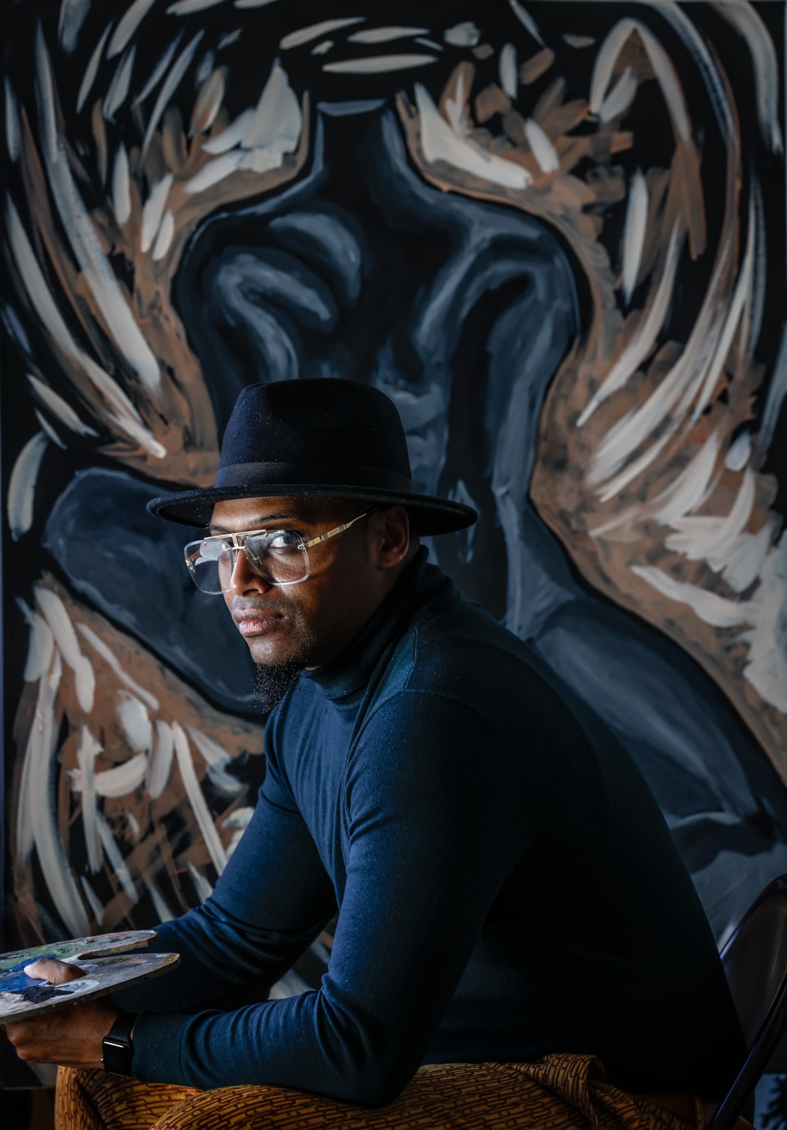 Dayton artist, Angelo Pierre works on a painting in the living room of his apartment in Dayton. JIM NOELKER/STAFF