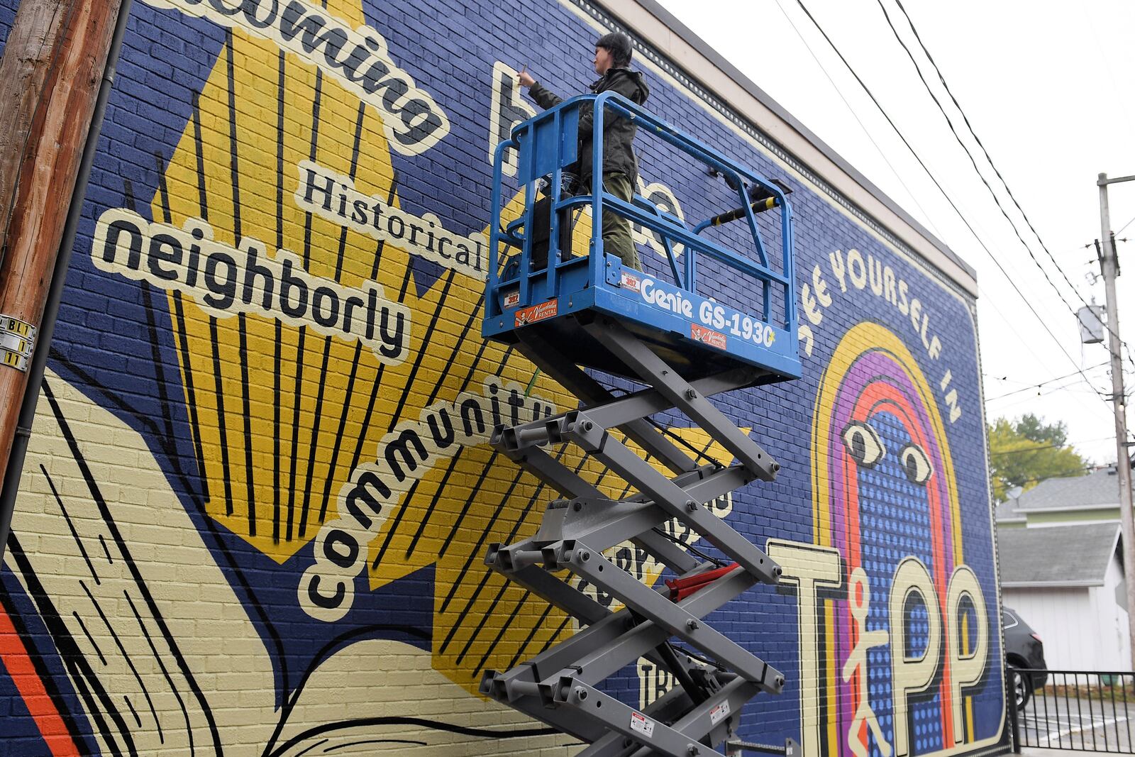 Atalie Gagnet, a Tippecanoe High School graduate known for her murals, works on finishing a mural on the east wall of the Tipp City Public Library on Oct. 22.  CONTRIBUTED