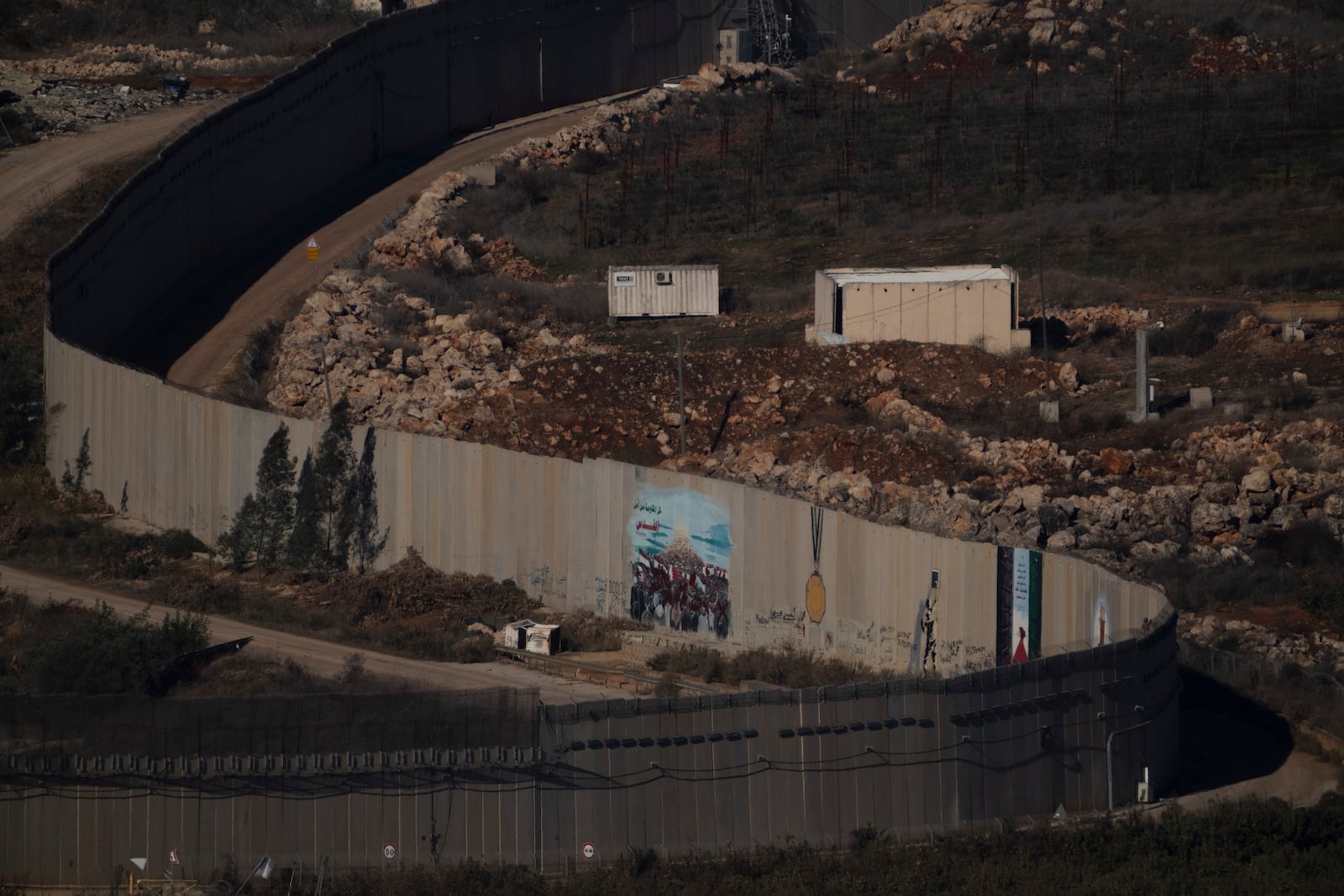 A wall marks the Israeli-Lebanese border near the village of Odaisseh in southern Lebanon, as seen from northern Israel, Sunday, Dec. 1, 2024. (AP Photo/Leo Correa)