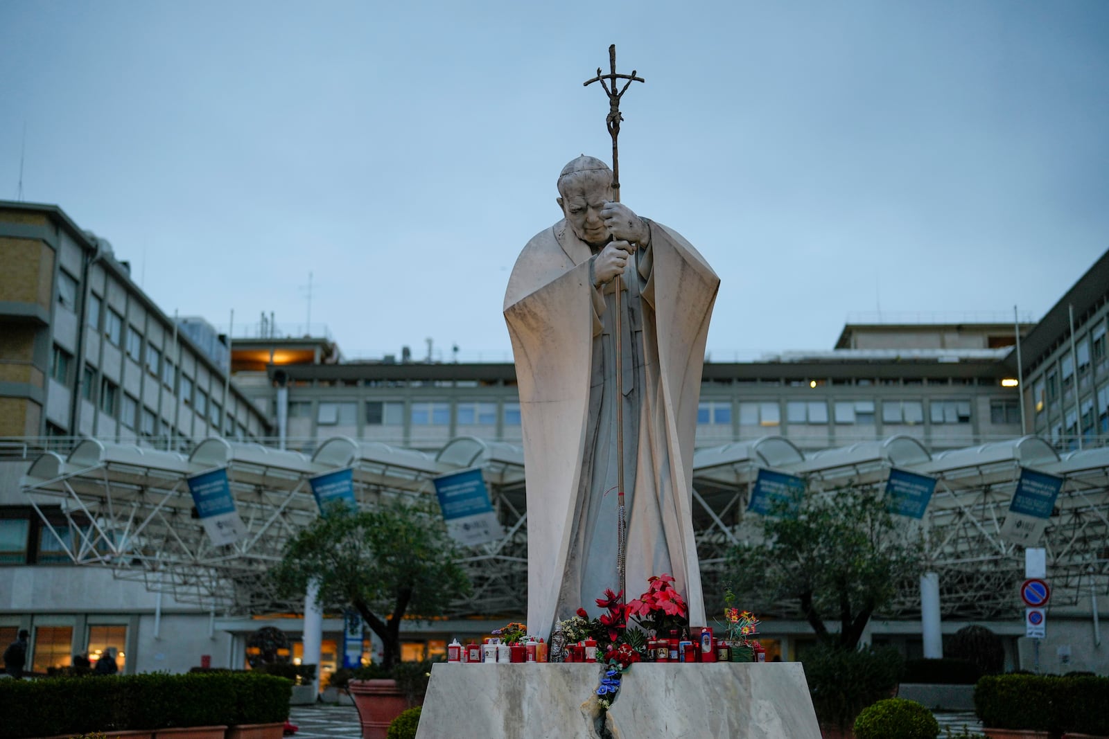 A marble statue of late Pope John Paul II is backdropped by the Agostino Gemelli Polyclinic in Rome, Saturday, Feb. 15, 2025, where Pope Francis was hospitalized Friday after a weeklong bout of bronchitis worsened and is receiving drug therapy for a respiratory tract infection. (AP Photo/Gregorio Borgia)