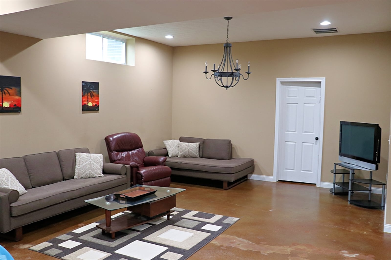 The basement has a stained concrete floor and support columns that divide the space into the living space. 